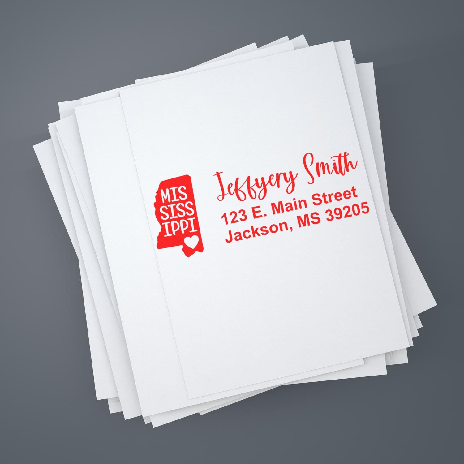 Custom rubber stamp return address for Mississippi mailings on stacked white paper.