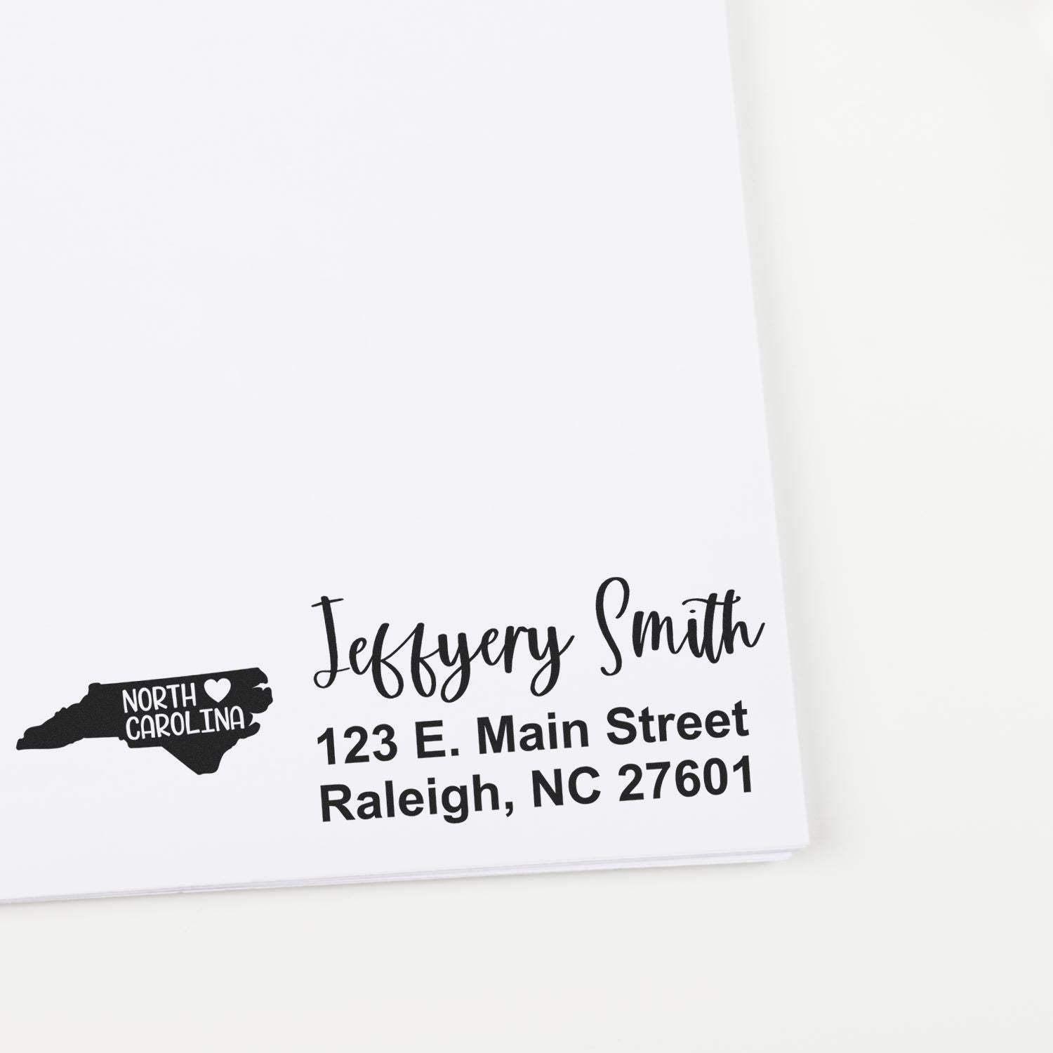 Custom return address rubber stamp with North Carolina state icon, name, and Raleigh mailing address.