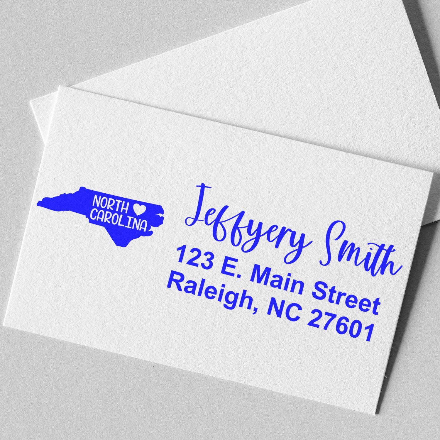 Custom return address rubber stamp for envelopes with North Carolina logo, Jeffrey Smith, and Raleigh, NC 27601.