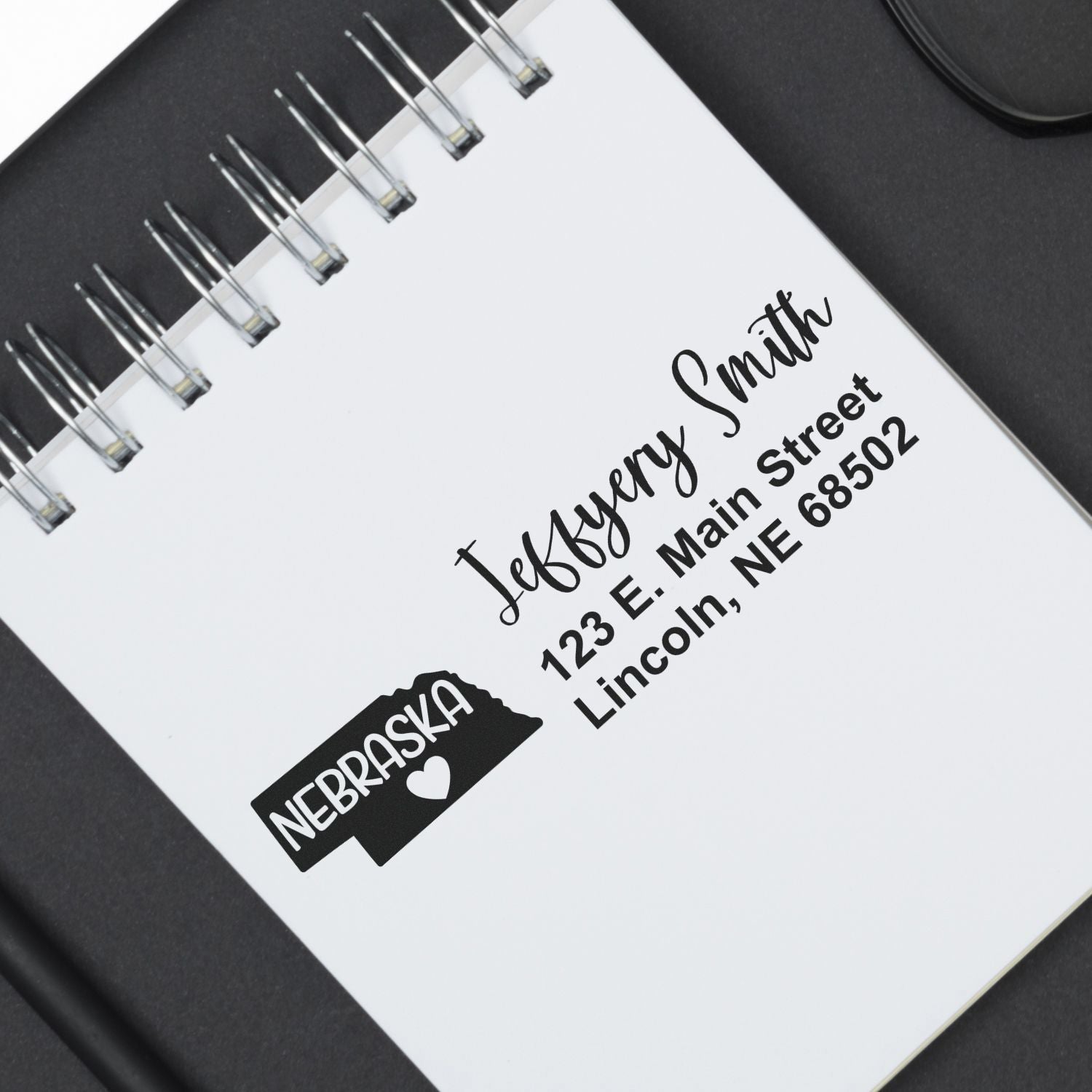 Custom rubber address stamp impression with Nebraska icon on a spiral notebook page