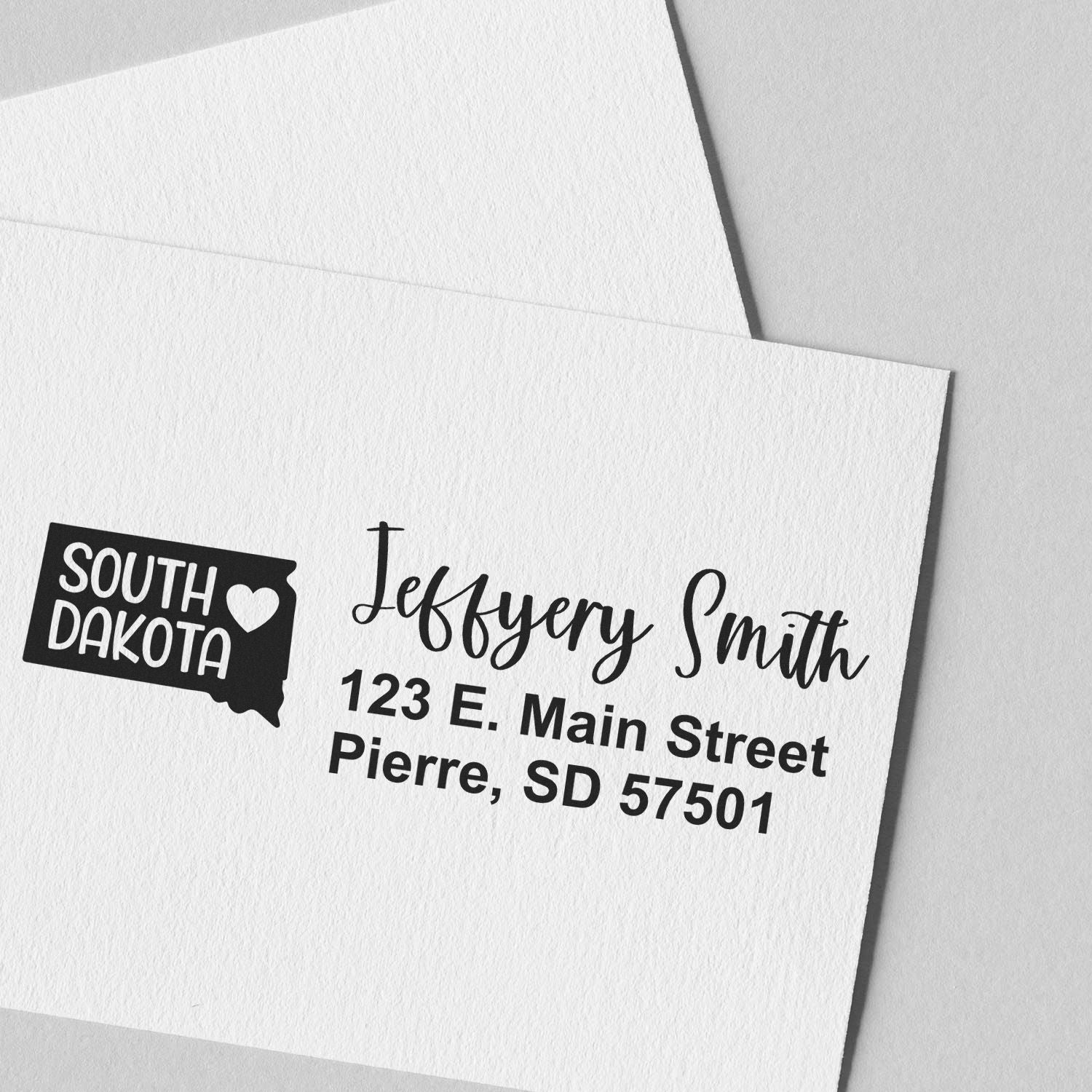 Custom return address rubber stamp with South Dakota state outline, personalized name, and mailing address on envelope.