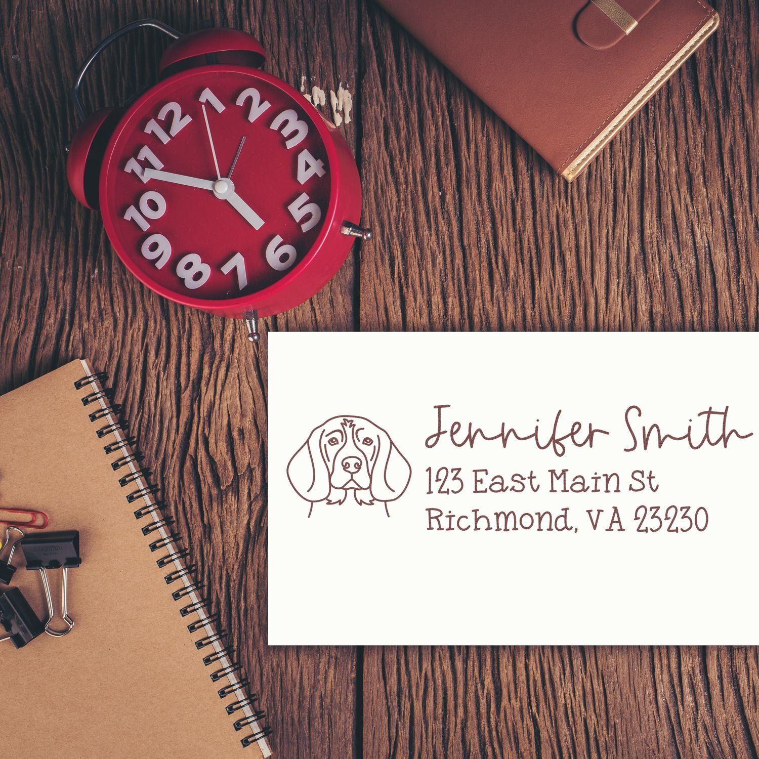 Custom rubber return address stamp with dog logo and Jennifer Smith address on paper, displayed on a rustic desk.