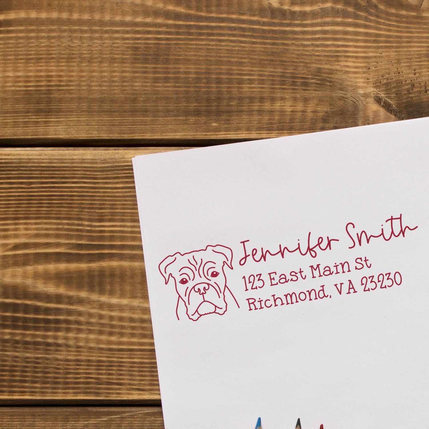Custom rubber address stamp with dog illustration, name, and mailing address in red ink on white paper.