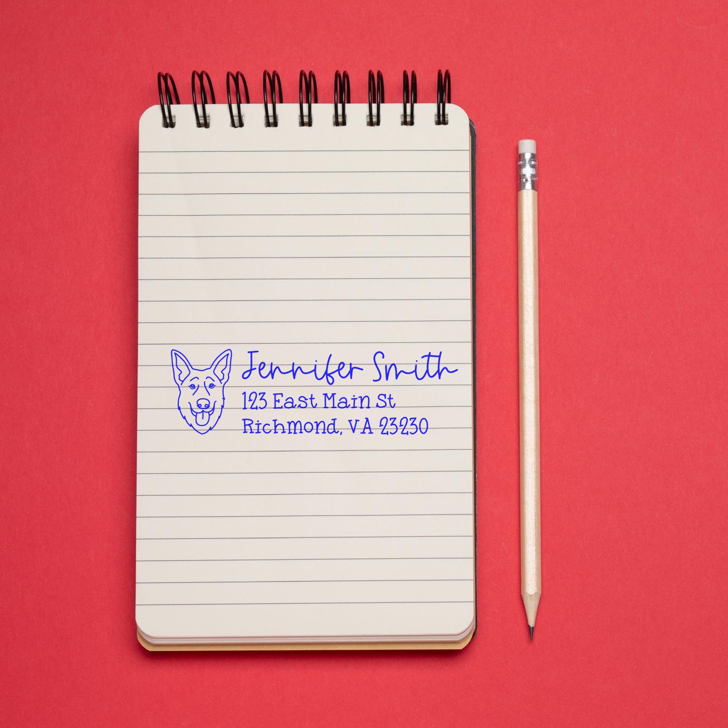 Custom return address rubber stamp with dog logo on notebook, ideal for personalized mailing and stationery.