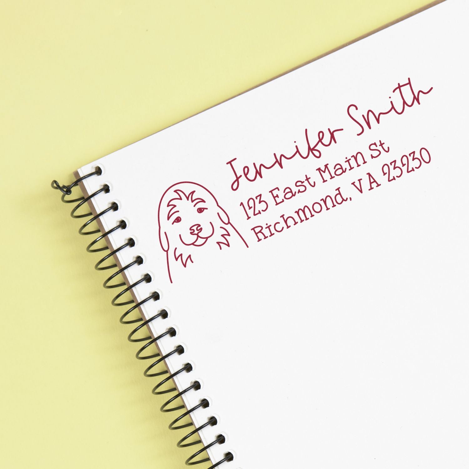 Custom return address rubber stamp with dog logo for Jennifer Smith on a spiral notebook.