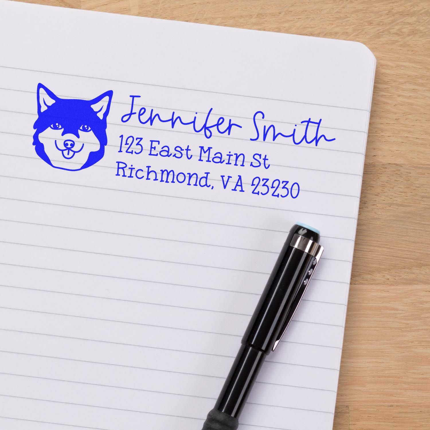 Custom dog return address rubber stamp on lined notebook, showing personalized name and mailing address in blue ink.