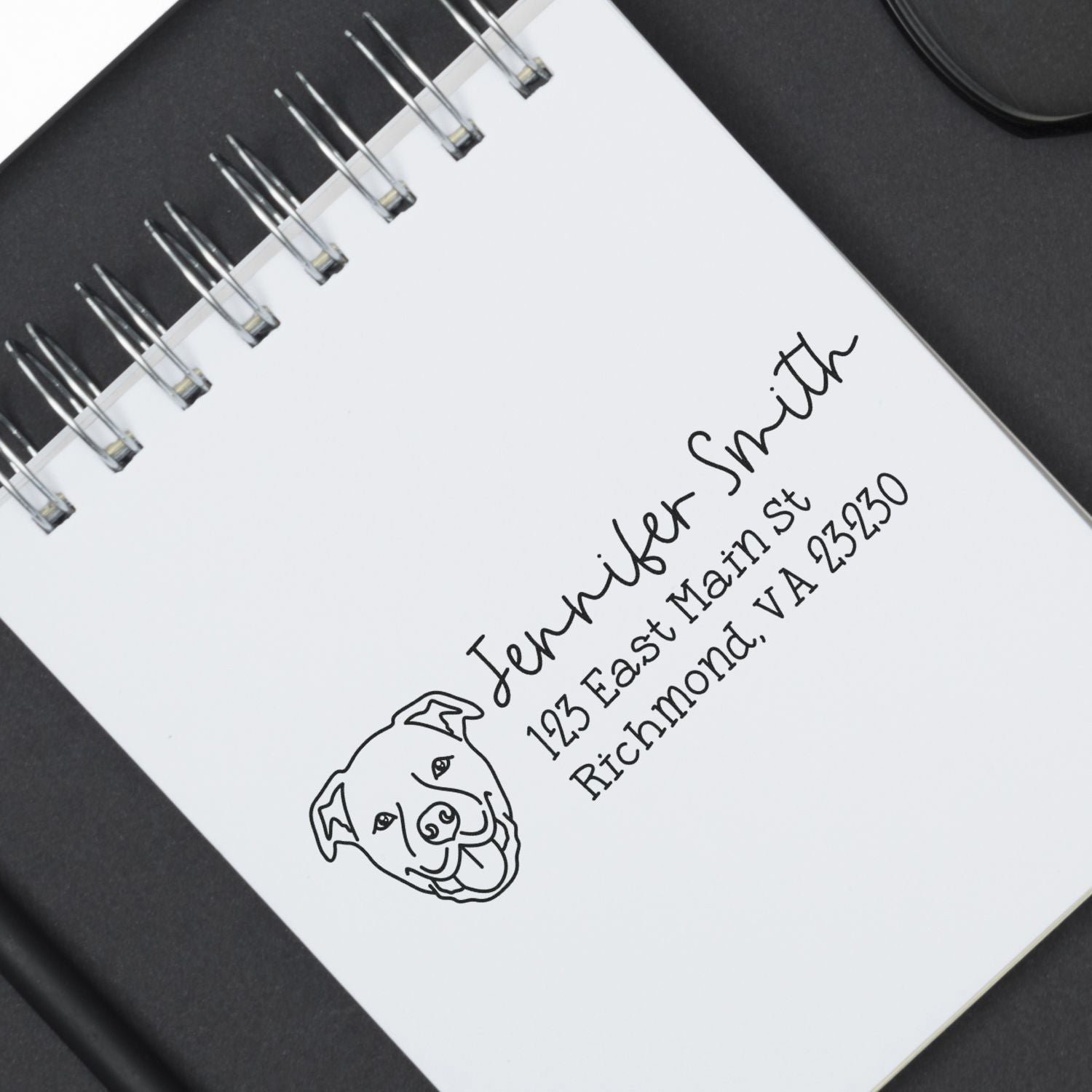 Personalized dog logo return address rubber stamp on spiral notebook, featuring Jennifer Smith, Richmond, VA 23230.