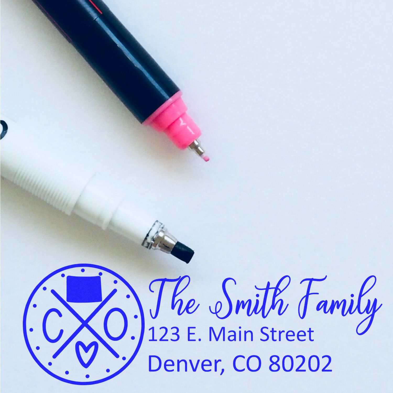 Custom self-inking rubber stamp sample with family name, address, and logo in blue ink.