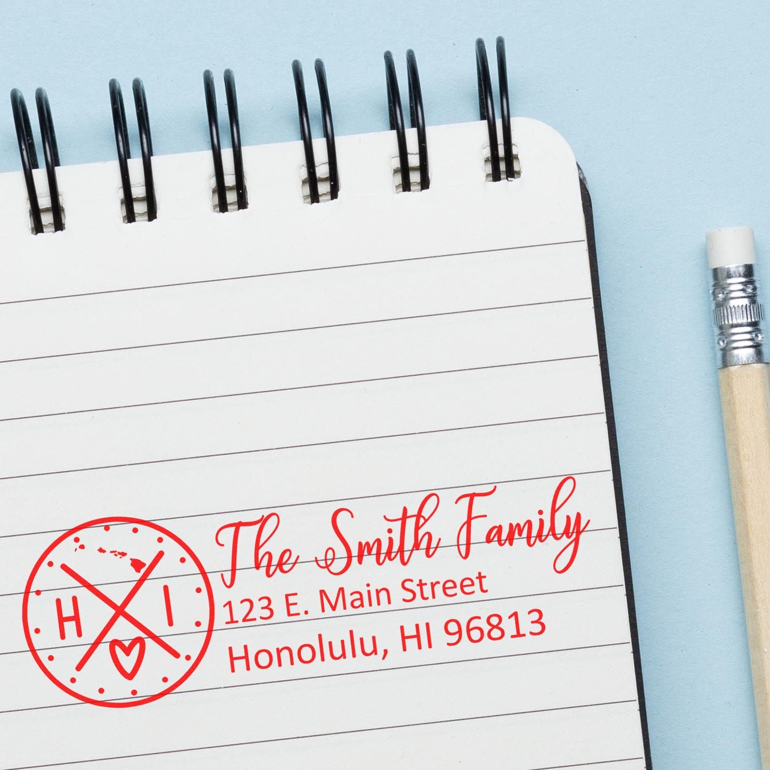 Custom family rubber stamp with return address and monogram logo on a notebook page, showing The Smith Family in red.