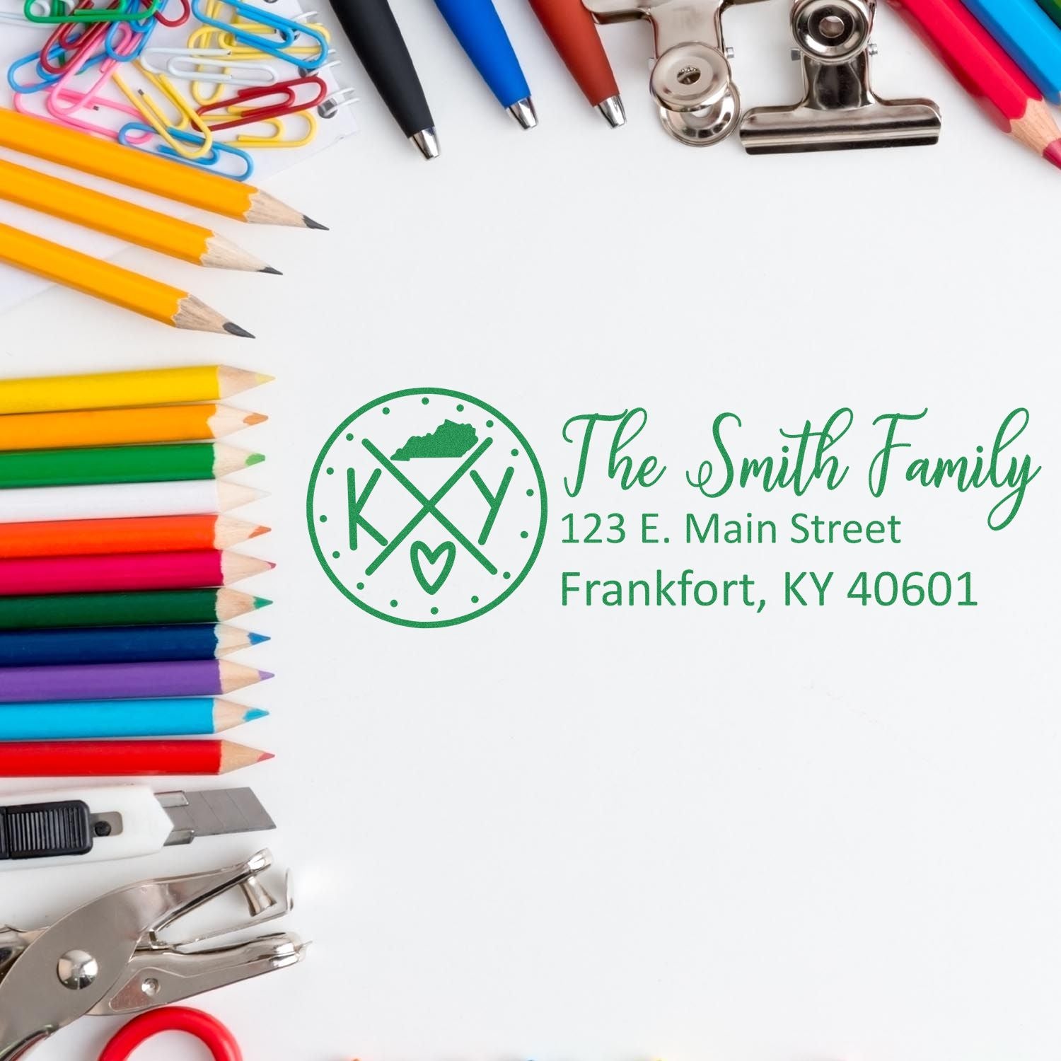 Custom rubber stamp with family monogram and return address for personalized mail, surrounded by pencils and office supplies.