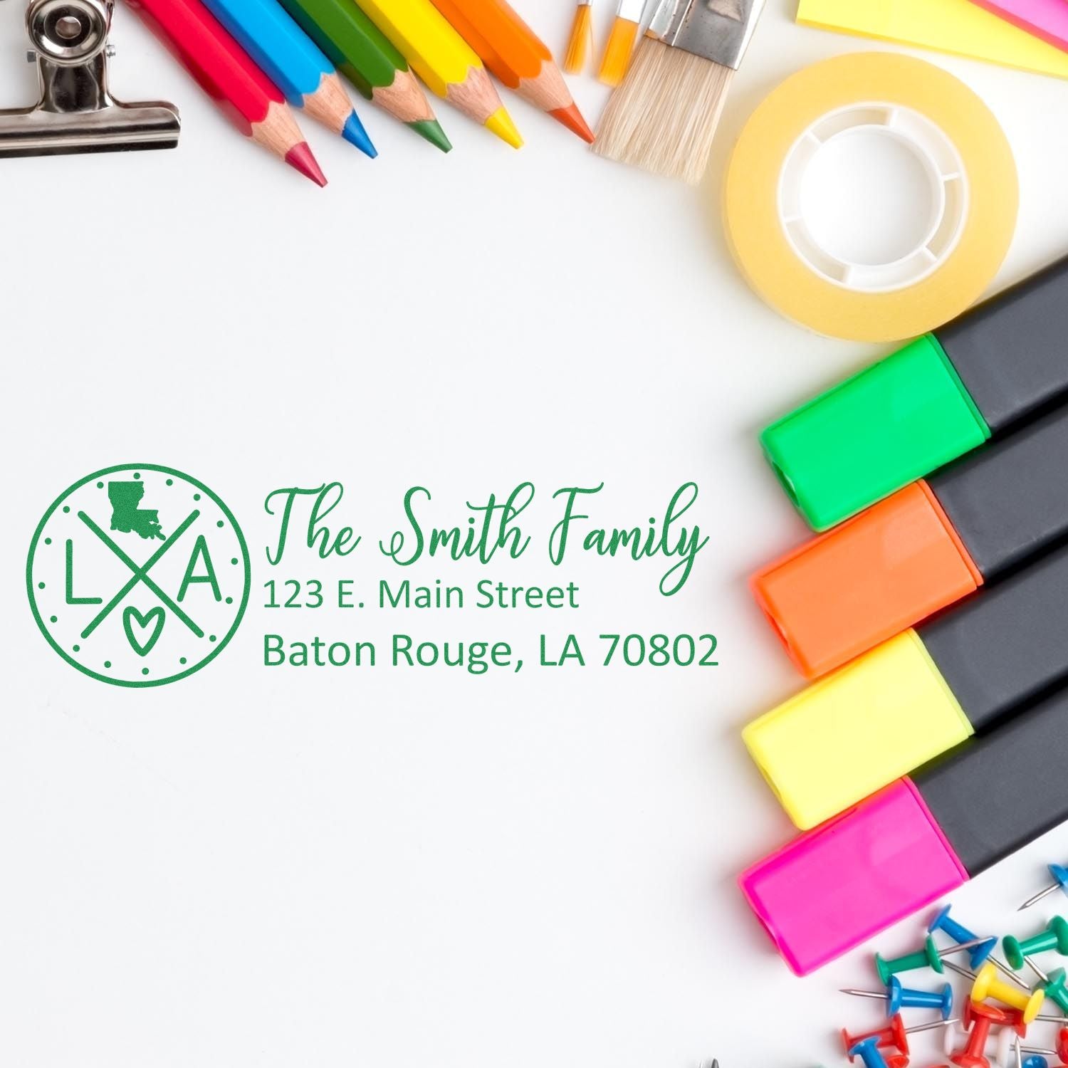 Personalized return address rubber stamp with family name and Baton Rouge, LA address, surrounded by colorful office supplies.