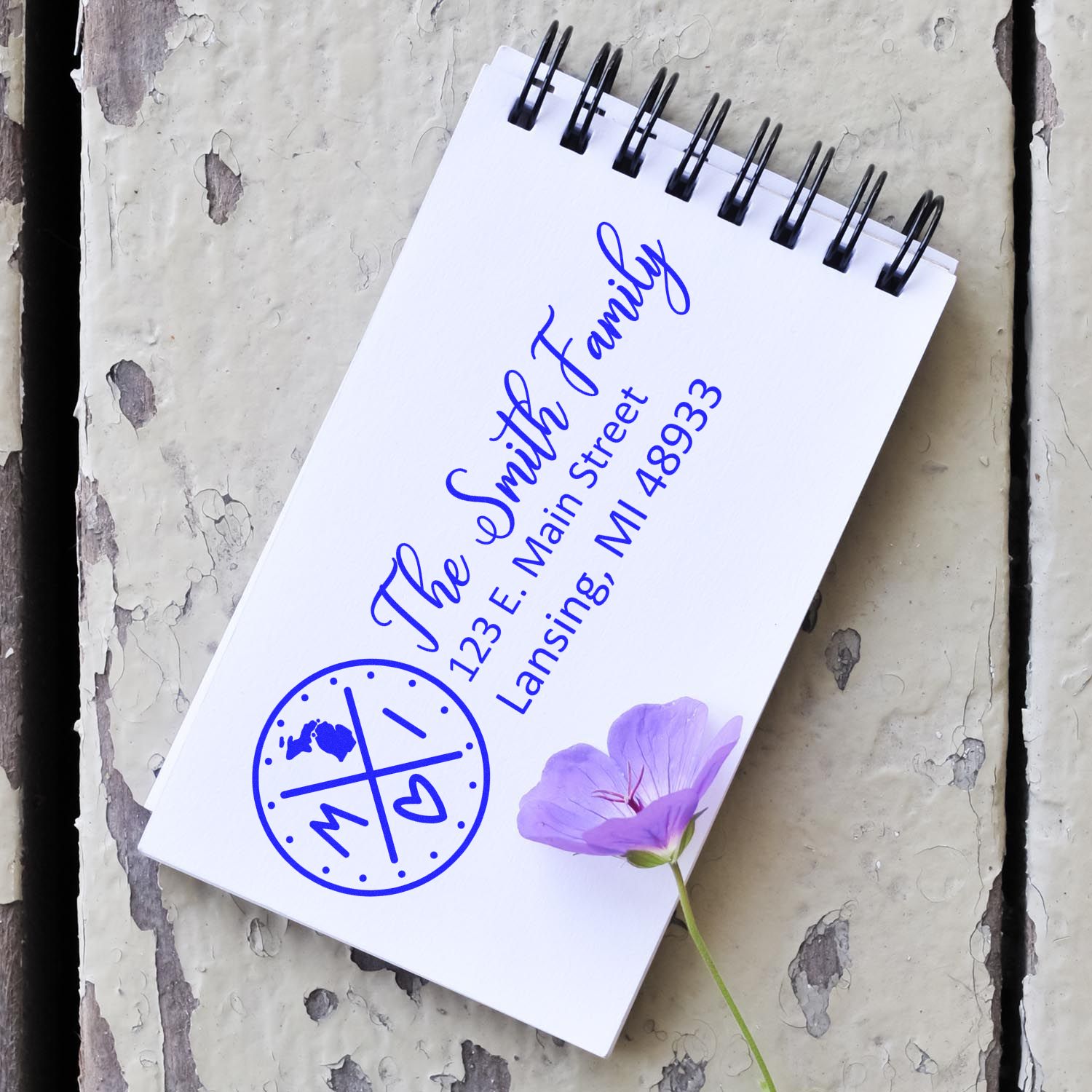 Custom family return address rubber stamp design showing name, monogram, and address on a spiral notepad.