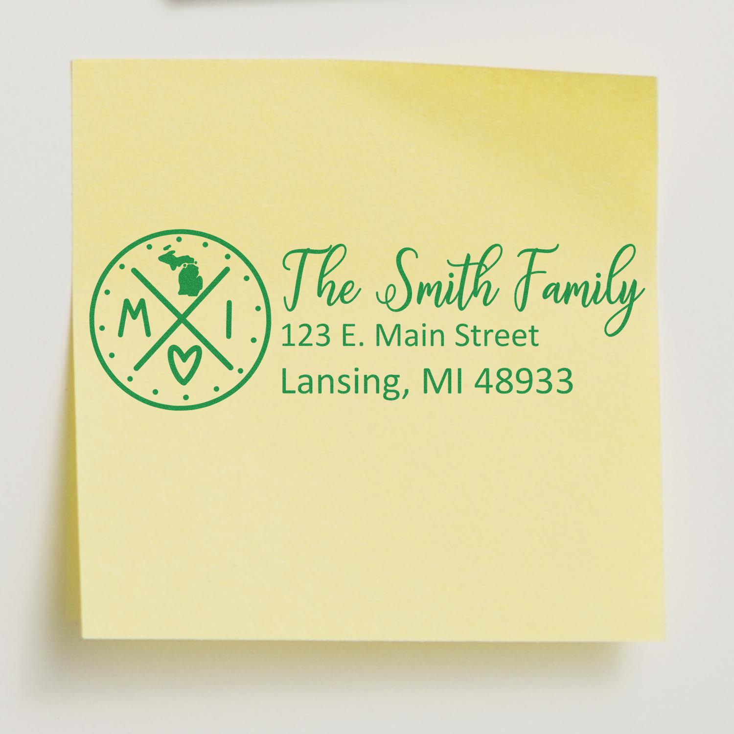 Custom family address rubber stamp with Michigan monogram and green ink imprint on a yellow note.