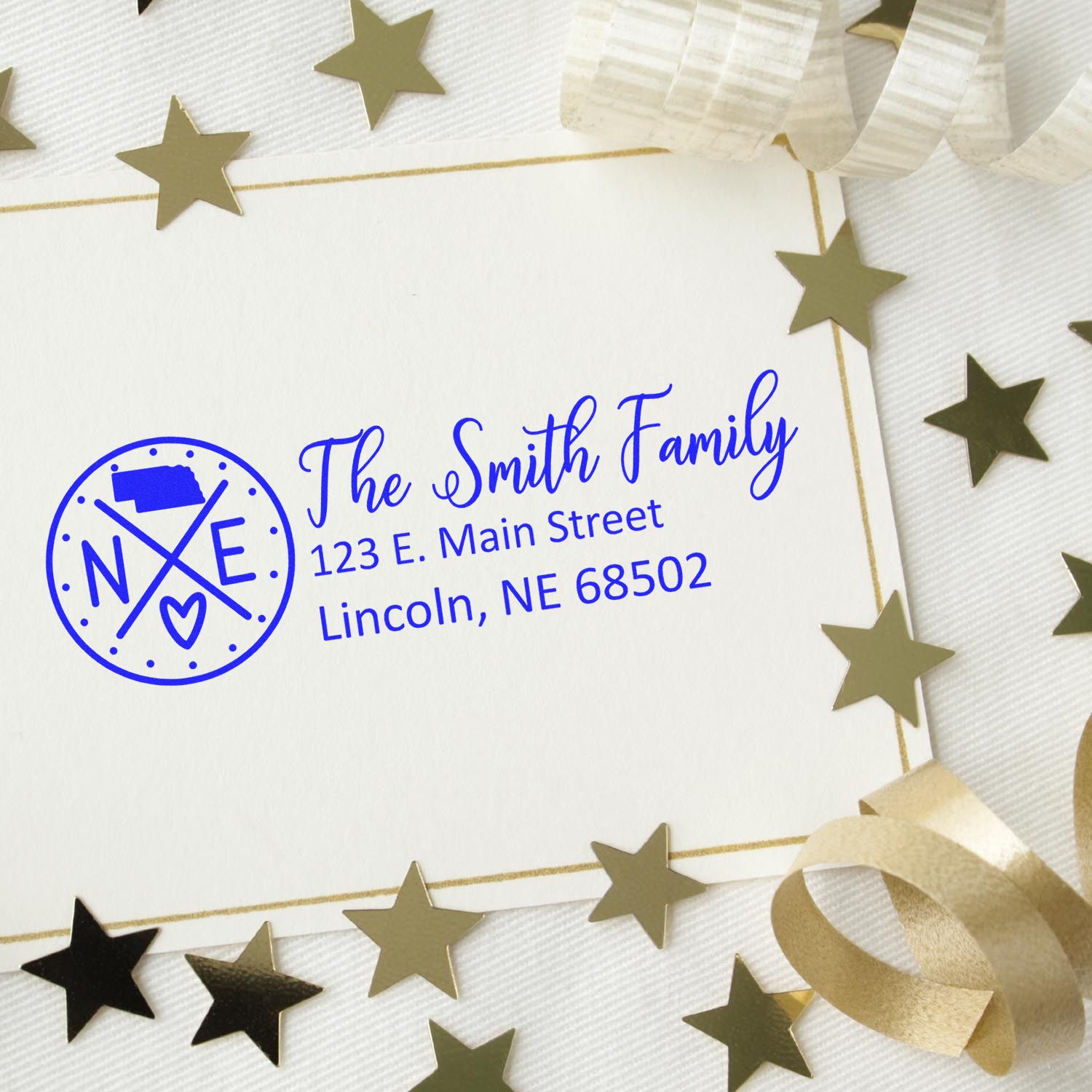 Custom address rubber stamp with family name and return address, shown on a festive card with gold star confetti.