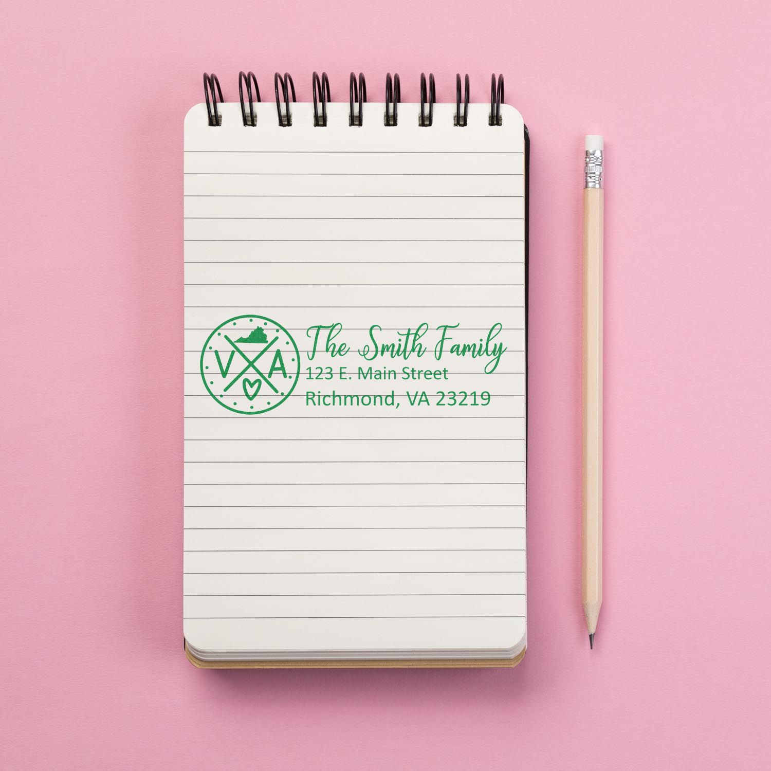 Personalized return address rubber stamp with family name and address, shown on a notebook for mail and stationery use.