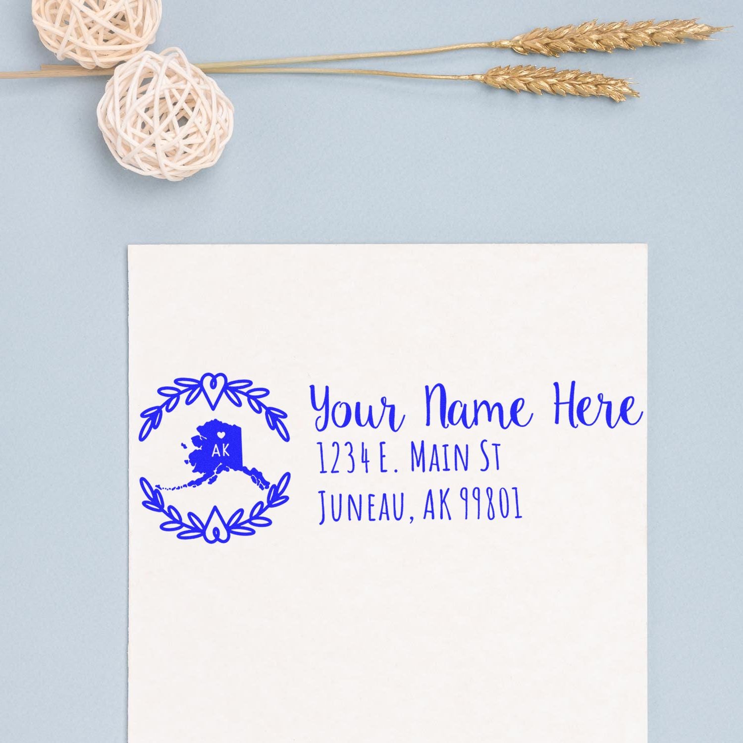 Custom Alaska return address rubber stamp with blue ink, featuring name, street address and Juneau, AK 99801 on white paper.