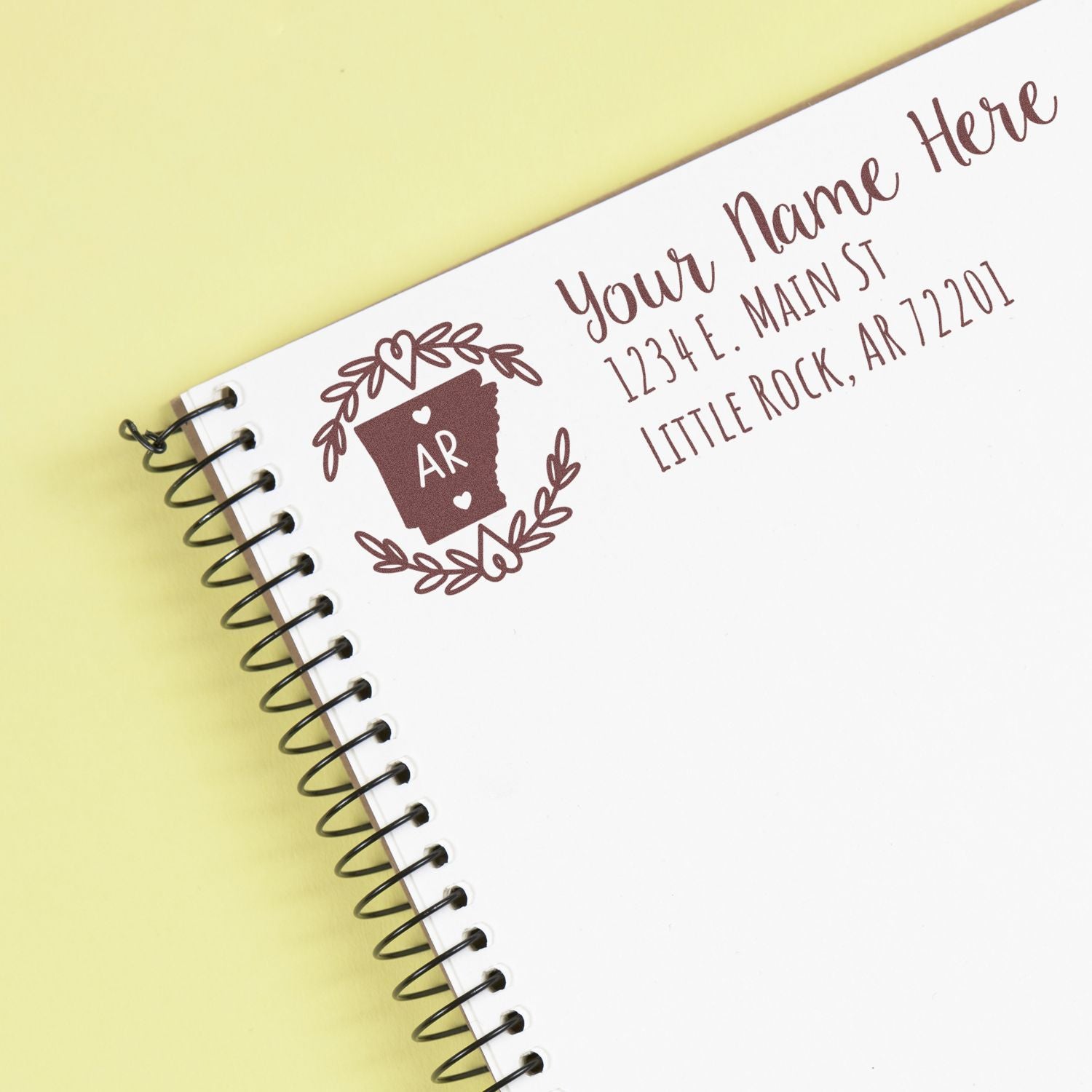 Personalized return address rubber stamp with monogram, name, and address on a notebook page for stationery or wedding use.