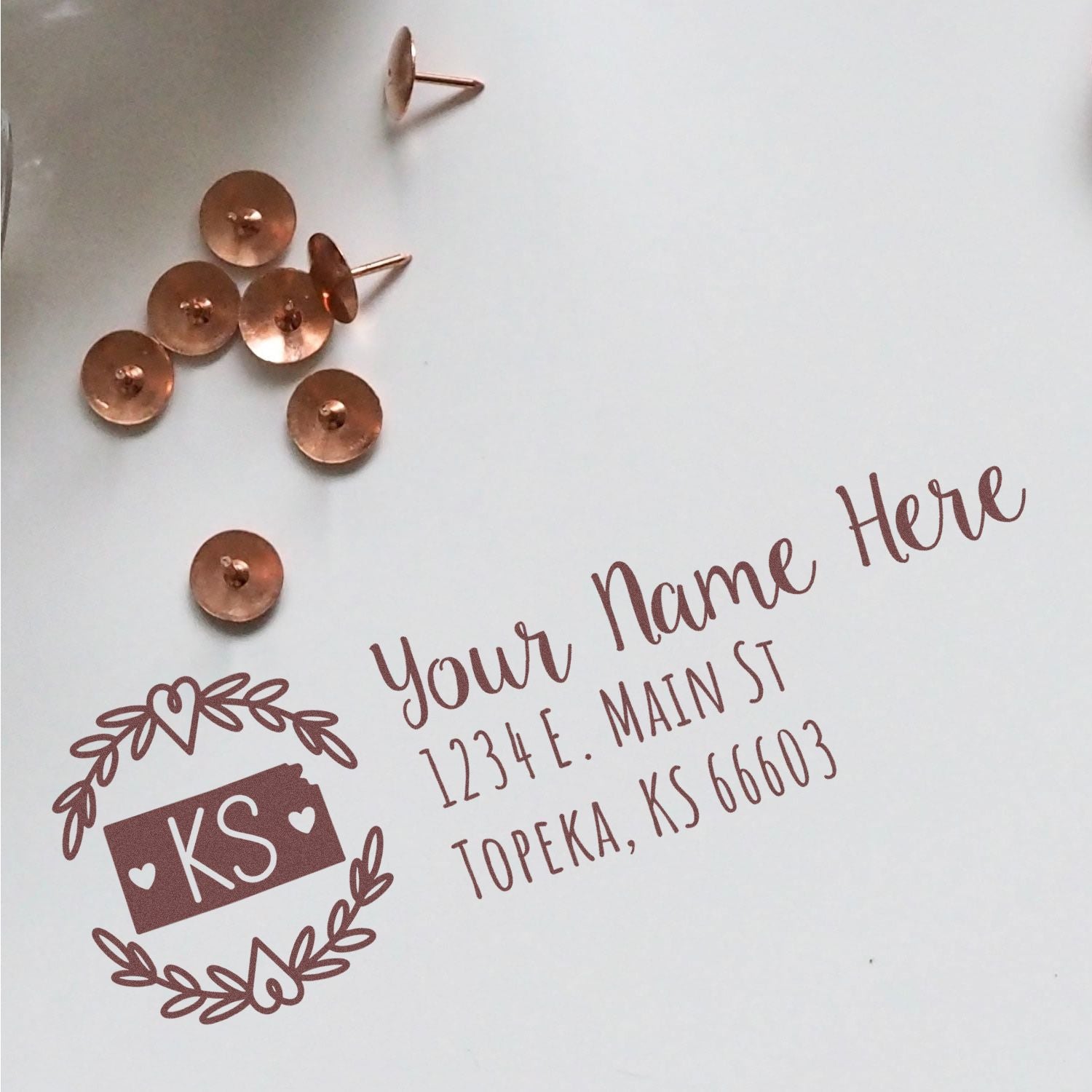 Custom return address rubber stamp with KS monogram wreath and personalized name and address on white envelope.