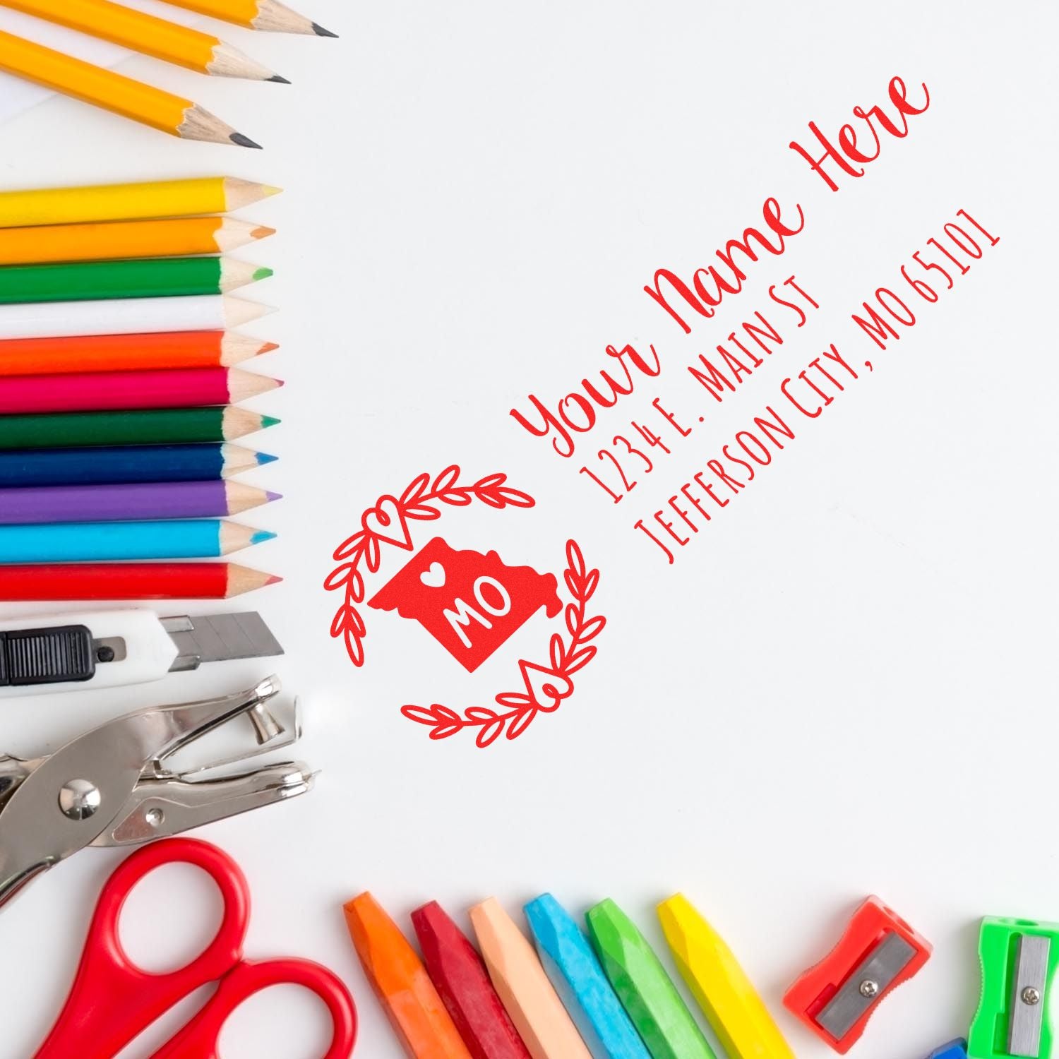 Custom rubber return address stamp impression with name and Jefferson City, MO, surrounded by colorful craft supplies.