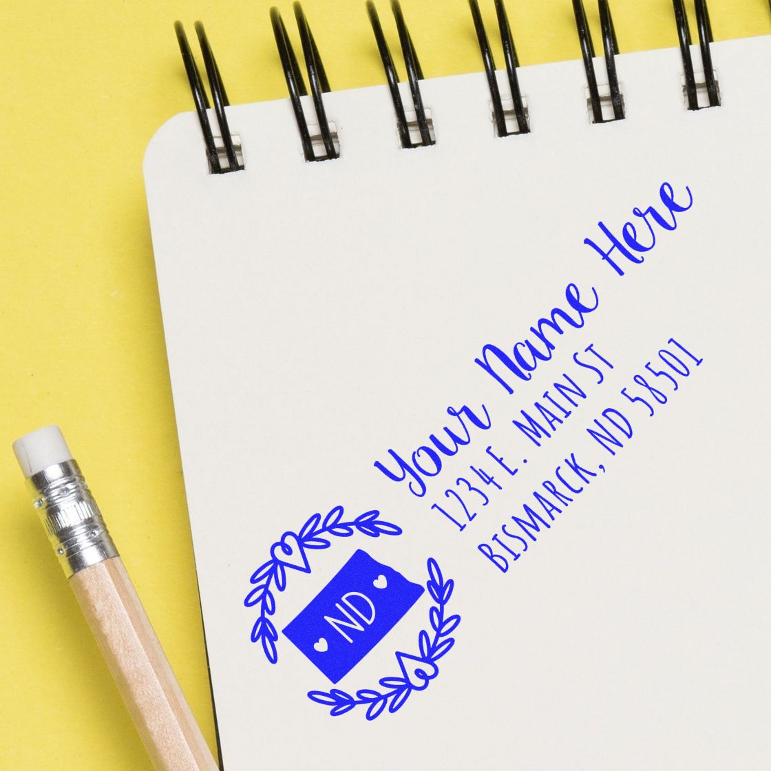 Custom rubber address stamp imprint on notebook, featuring name, ND monogram, and Bismarck, ND return address design.