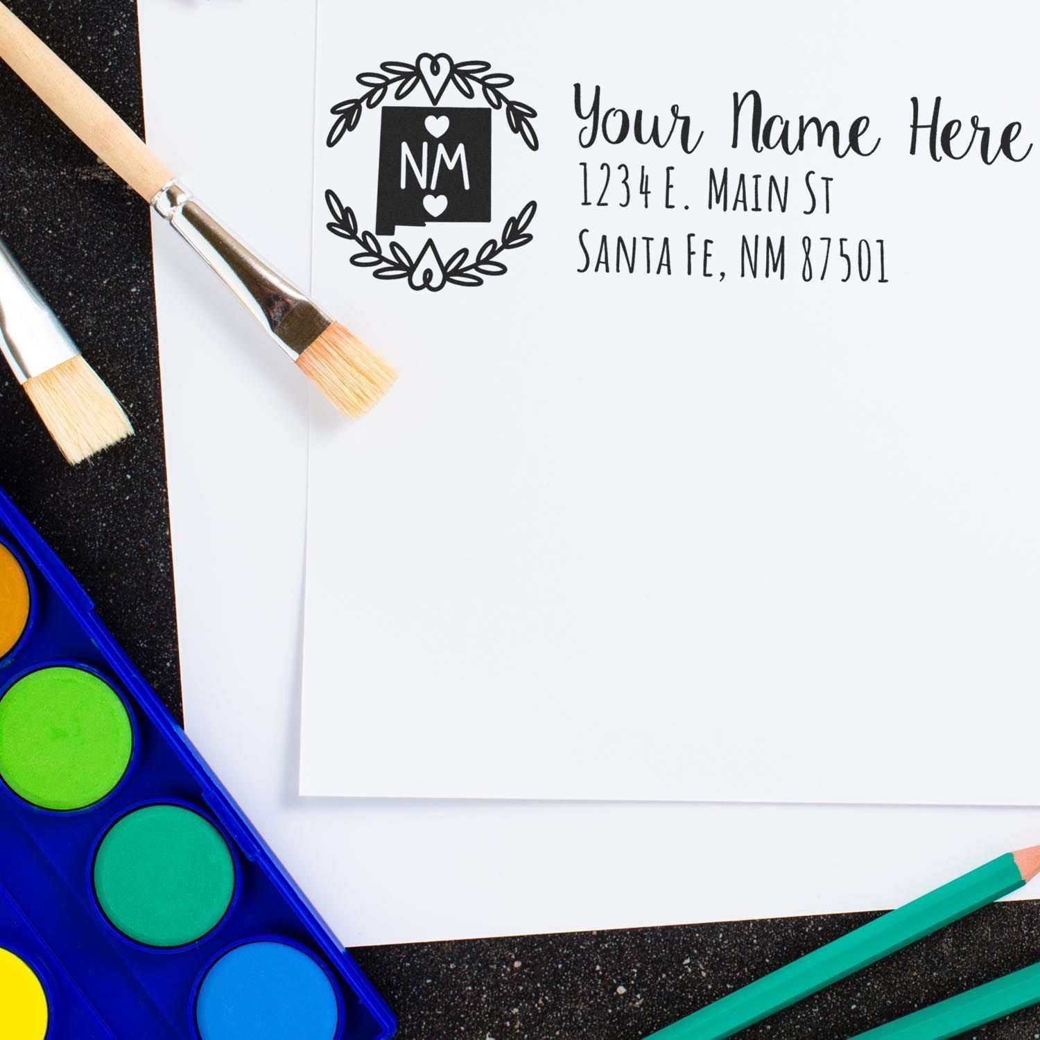 Custom return address rubber stamp with monogram and floral wreath, used on stationery for personalized mailing.