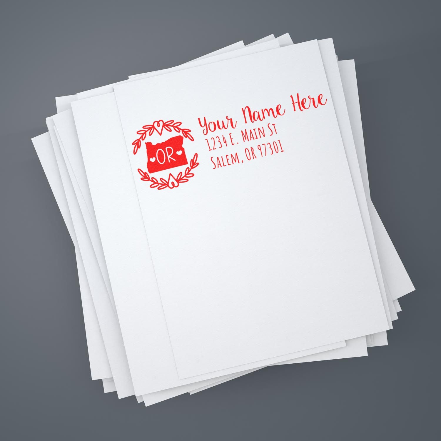 Custom rubber return address stamp with Oregon state design on stacked white stationery for mailing and branding.
