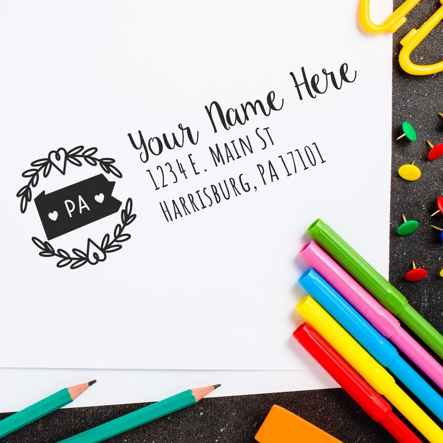 Custom return address rubber stamp sample with name, Harrisburg PA, on stationery with colorful pens.