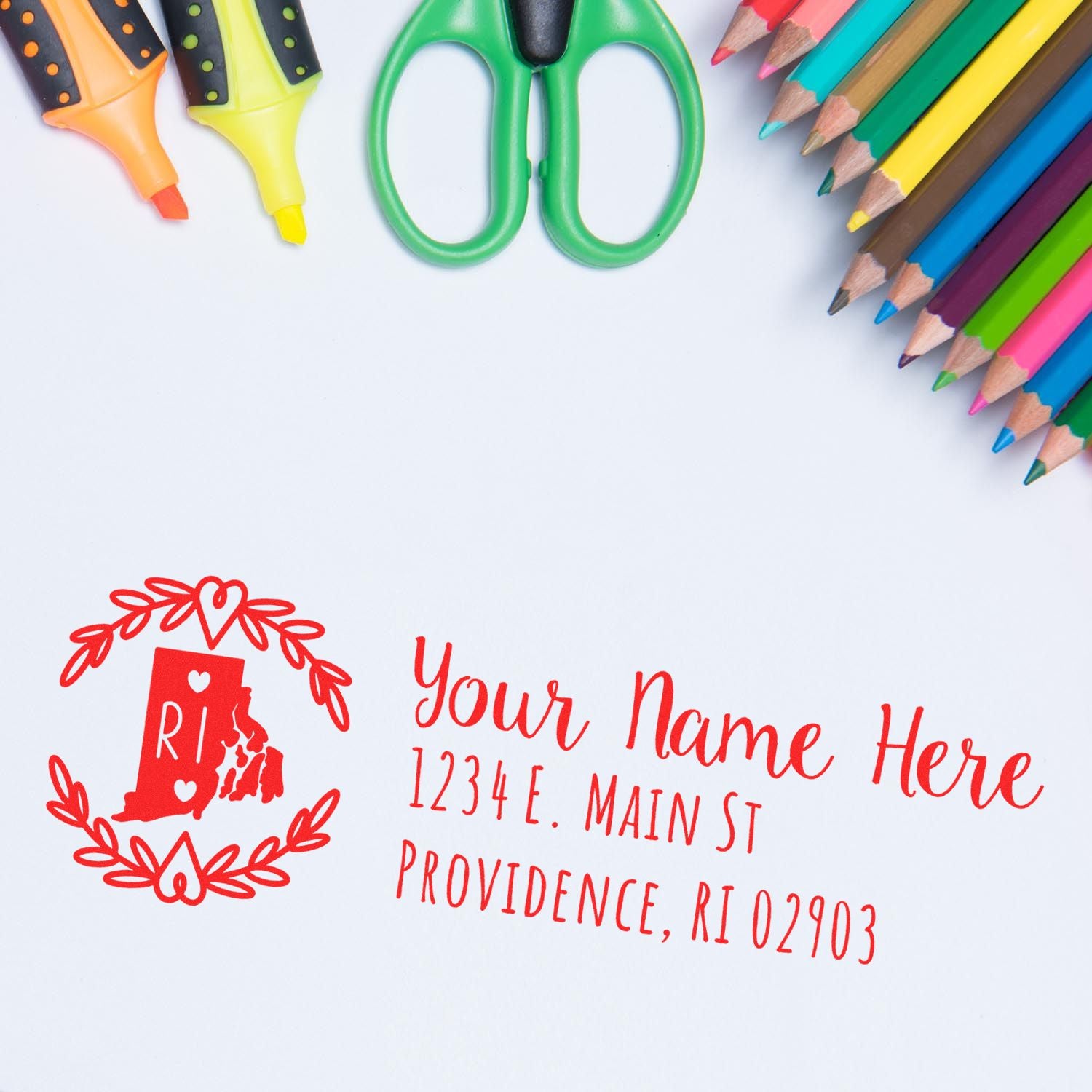 Custom return address rubber stamp with Rhode Island design, name, and mailing address, displayed with colorful school supplies.