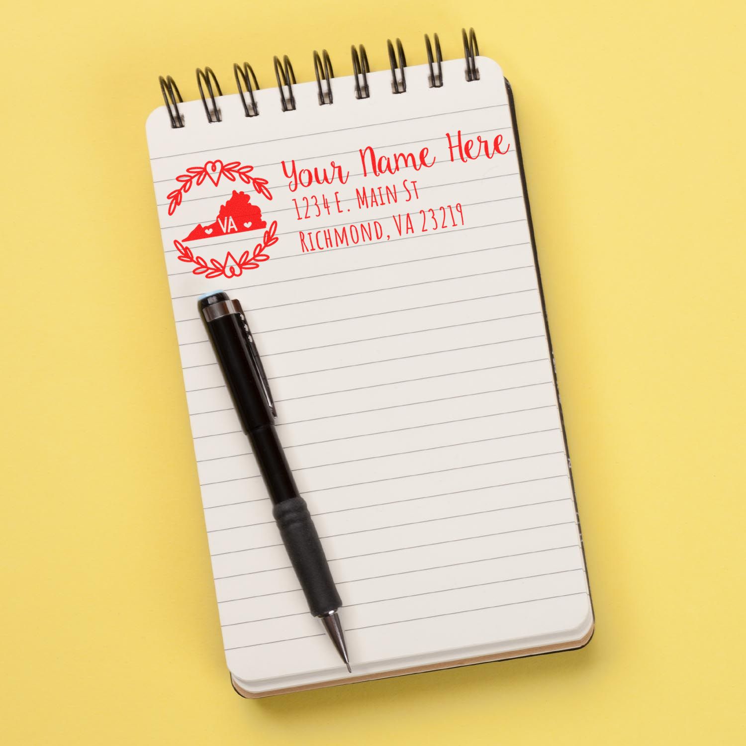 Custom Virginia return address rubber stamp design with name, street address, and state monogram on a notebook page.