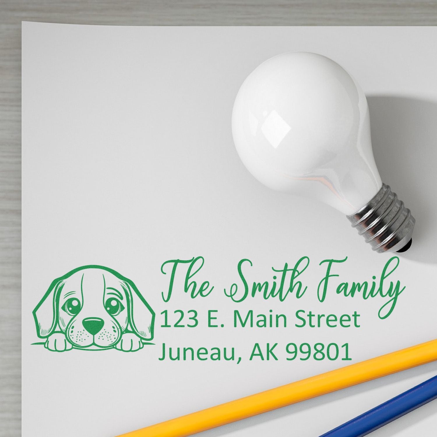 Custom return address rubber stamp with dog logo for family mailings, shown as a green imprint on paper.