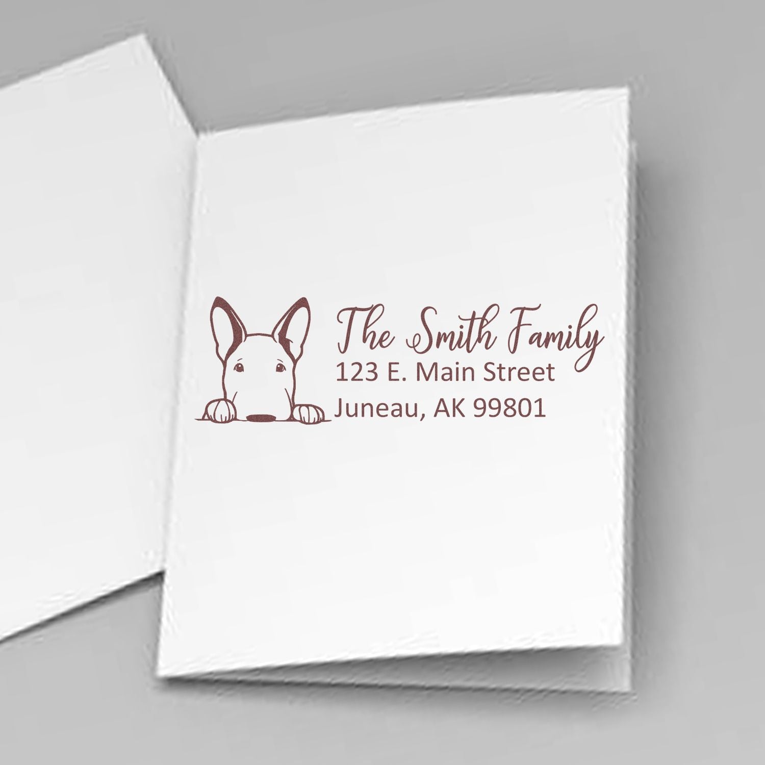 Custom rubber stamp on folded card with dog illustration and return address for The Smith Family, Juneau, AK.
