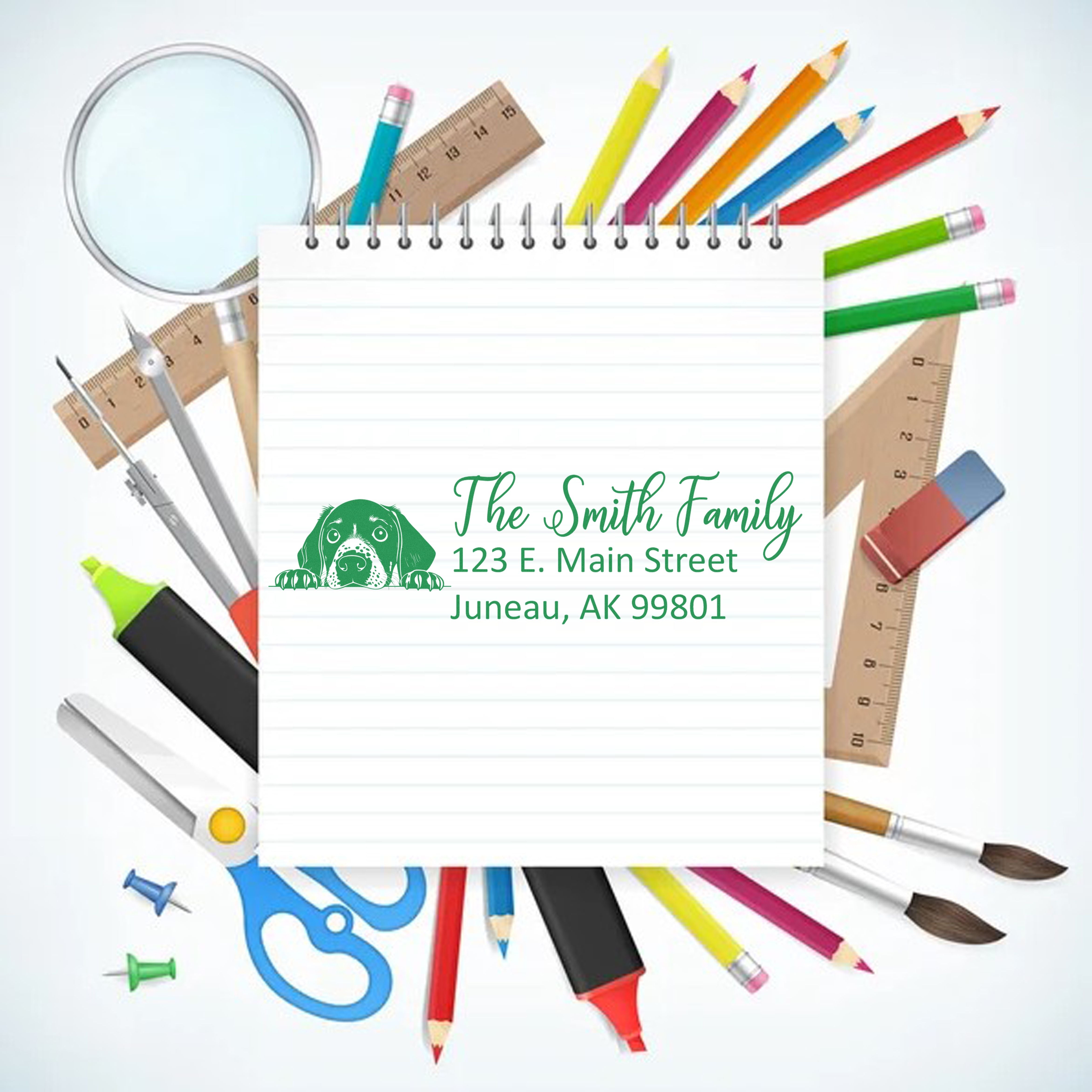 Custom return address rubber stamp with dog logo and family name, shown on a school supplies background.