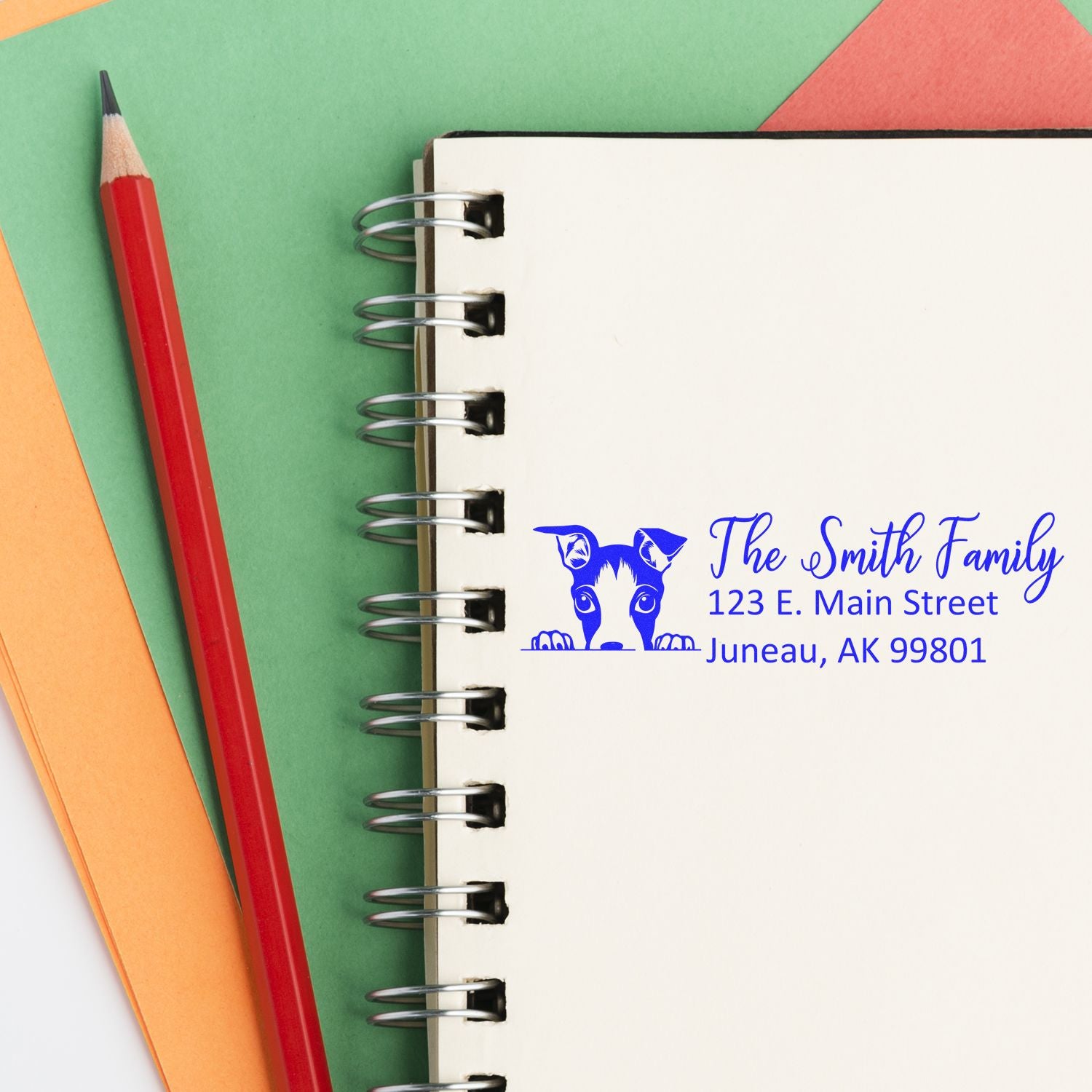 Custom dog family return address rubber stamp with personalized name and address on a notebook.