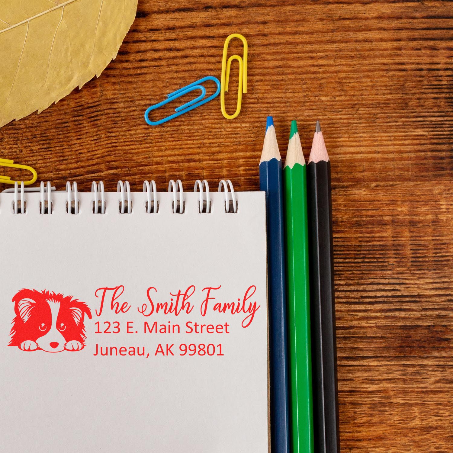 Custom return address rubber stamp with dog logo on notebook, featuring The Smith Family name and Juneau, Alaska address.