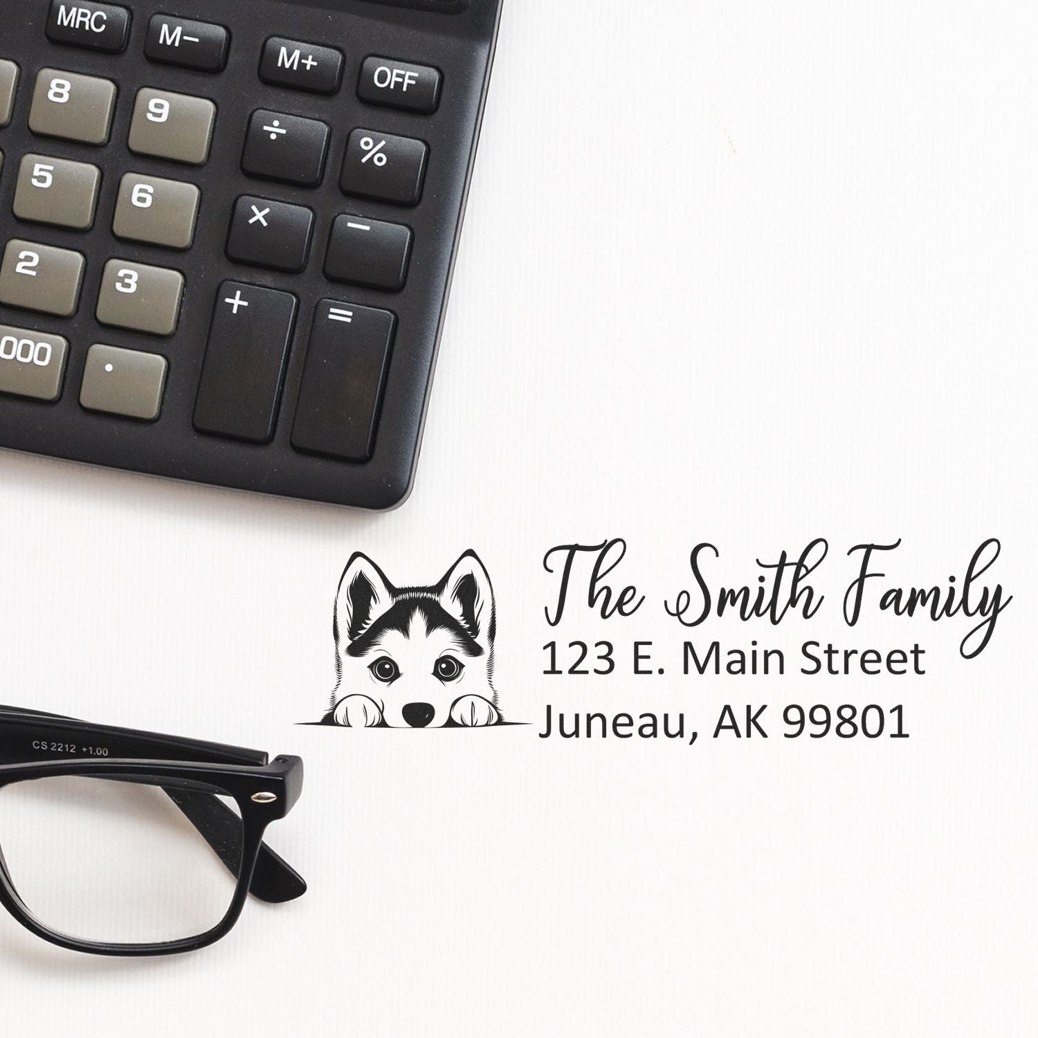 Custom rubber stamp design with husky dog, Smith family name and address, shown with calculator and glasses for home business use.