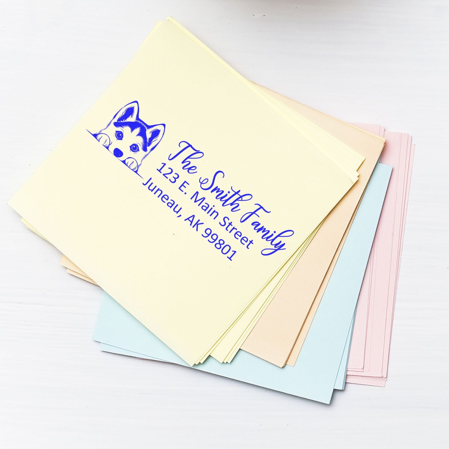 Custom return address rubber stamp with dog logo on pastel envelopes.