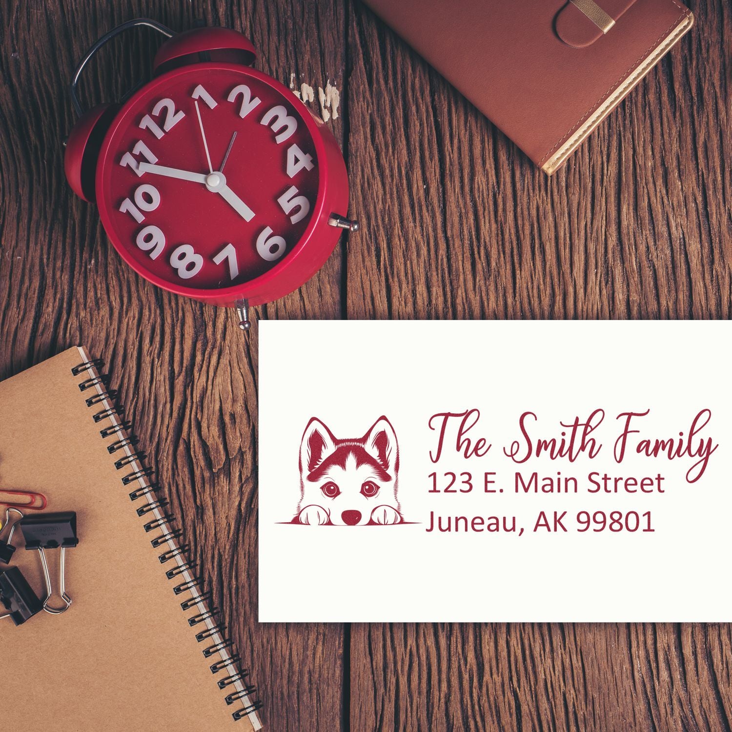 Custom rubber address stamp with family name and dog logo, displayed on a desk with clock and stationery.