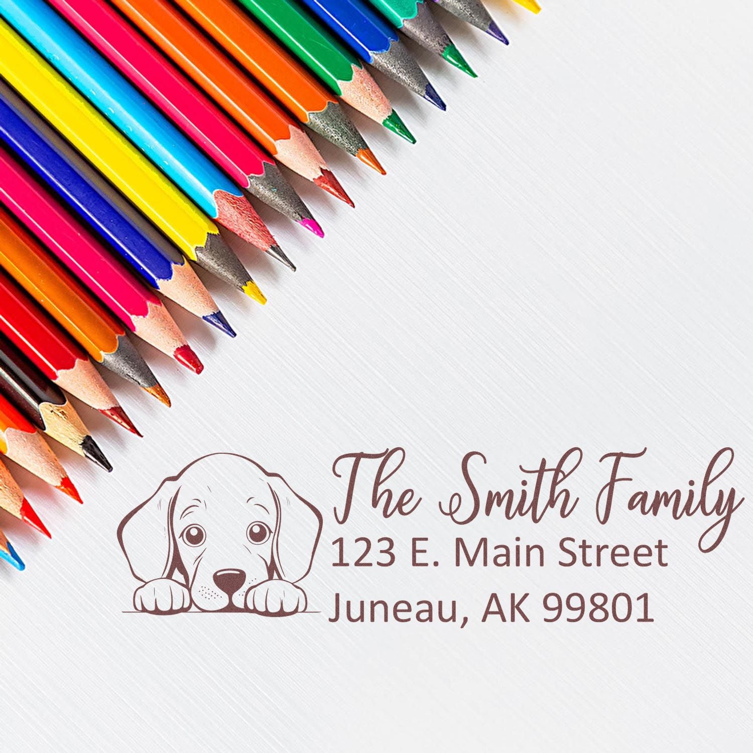 Personalized return address rubber stamp with dog logo, family name, and address, displayed with colorful pencils.