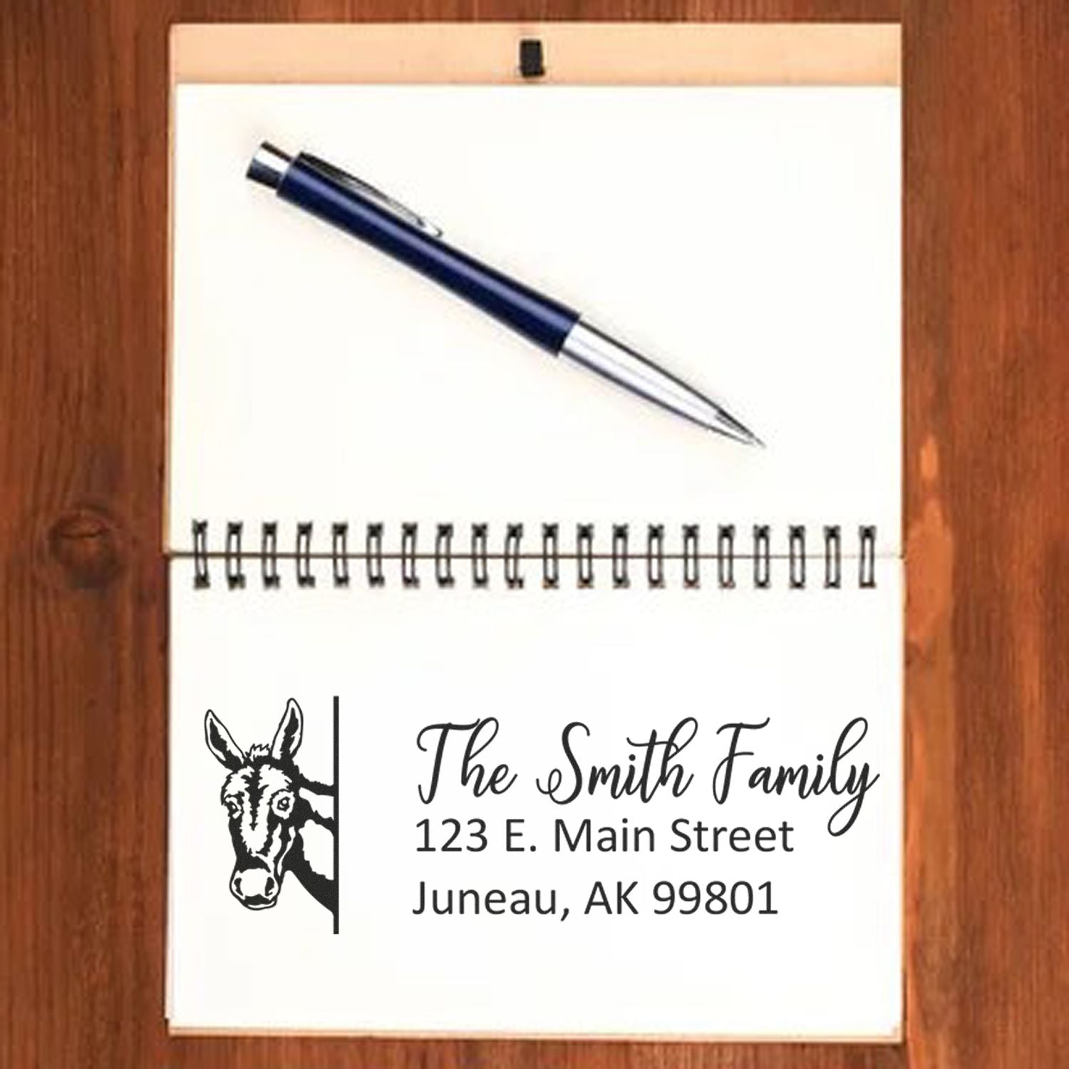 Custom rubber stamp return address design with donkey logo, The Smith Family, and Juneau, AK 99801, displayed with pen on notepad.