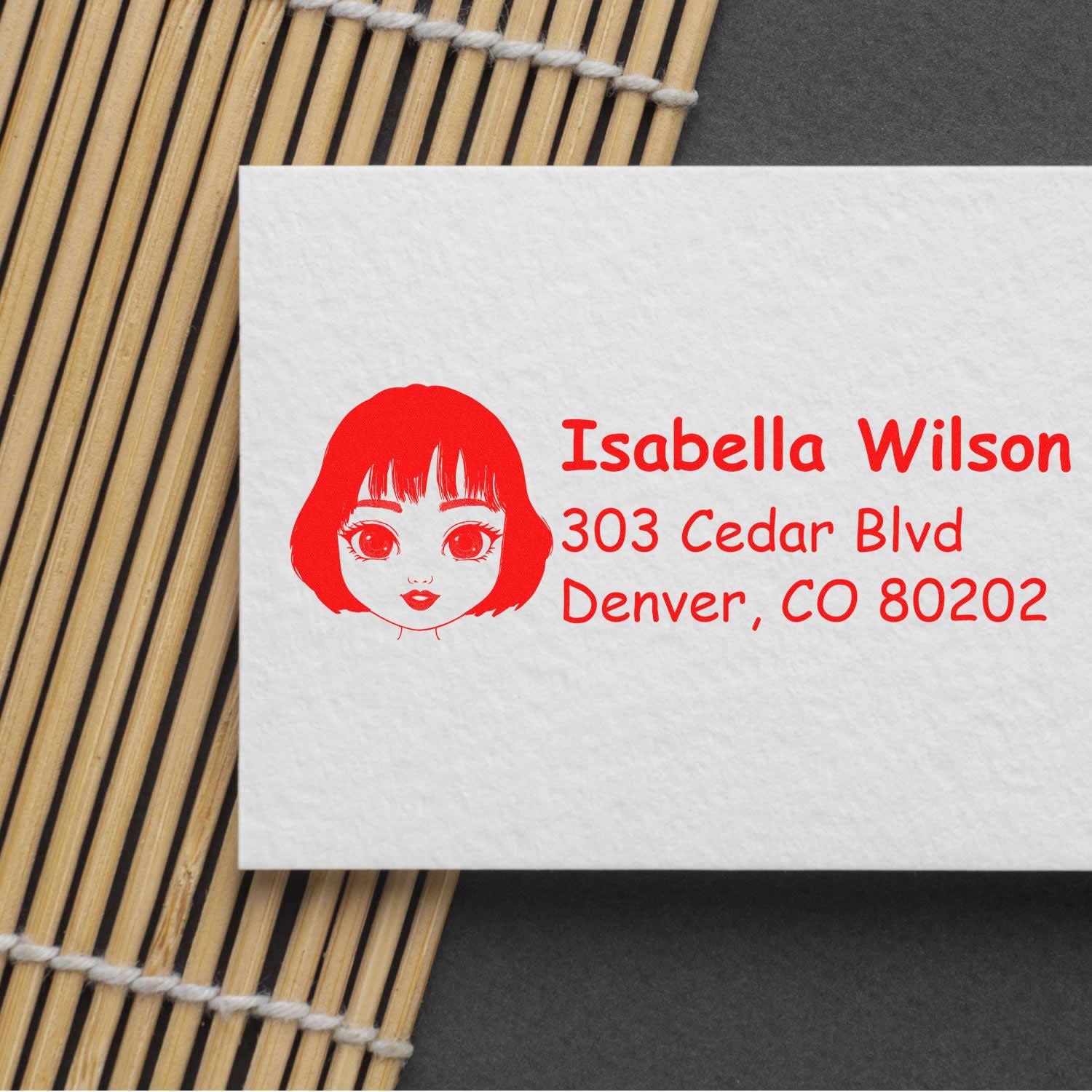 Personalized return address rubber stamp with girl face design, Isabella Wilson name, and Denver, CO address in red ink.