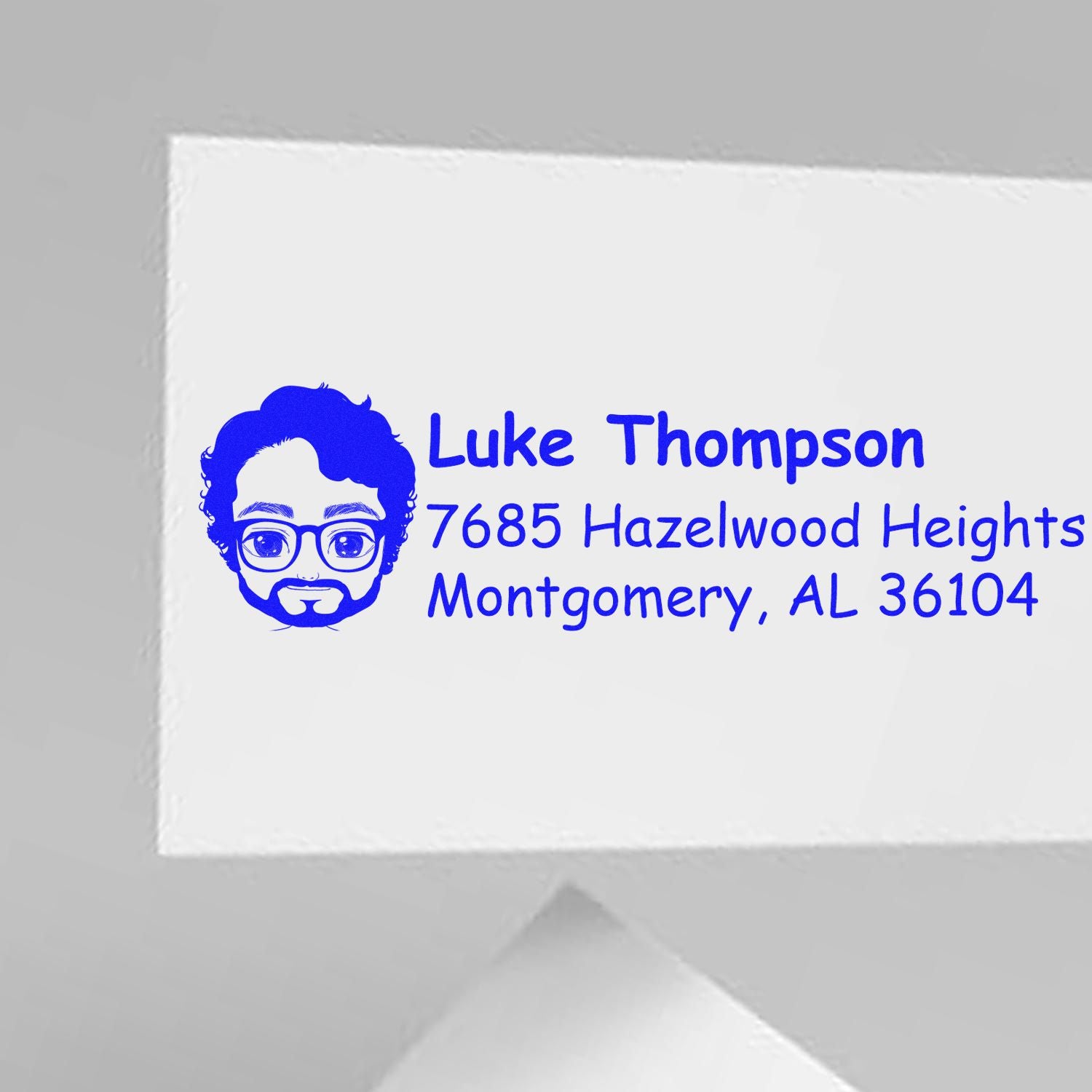 Custom rubber address stamp with avatar icon for Luke Thompson, 7685 Hazelwood Heights, Montgomery, AL 36104.