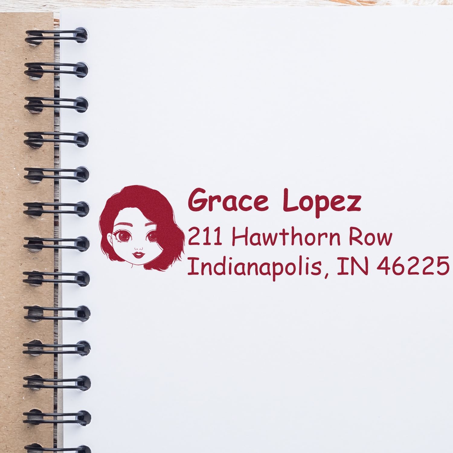 Custom return address rubber stamp with portrait logo, name, and address on notebook page for personalized mailing.