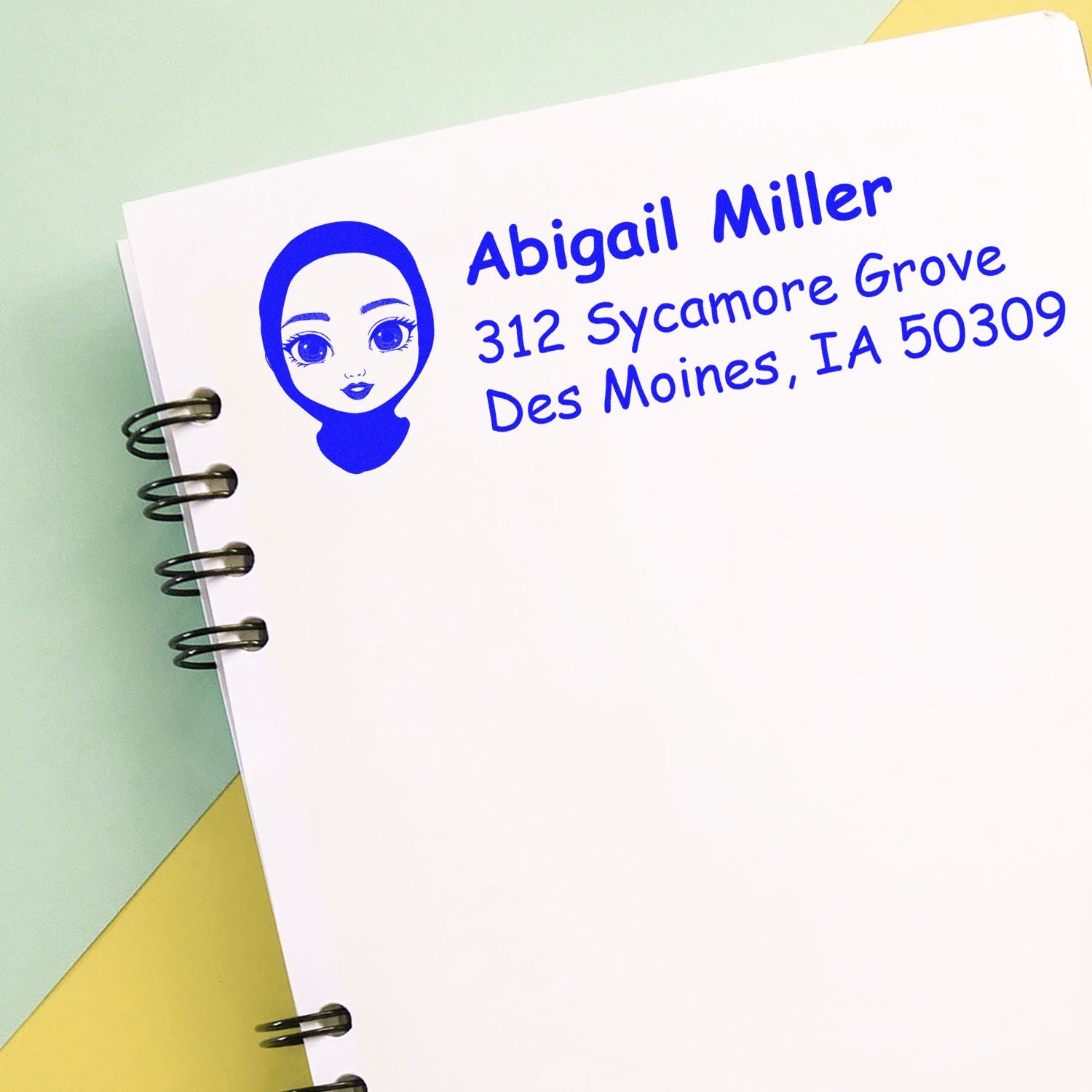 Personalized return address rubber stamp with avatar design and blue ink, featuring Abigail Millers Des Moines address.