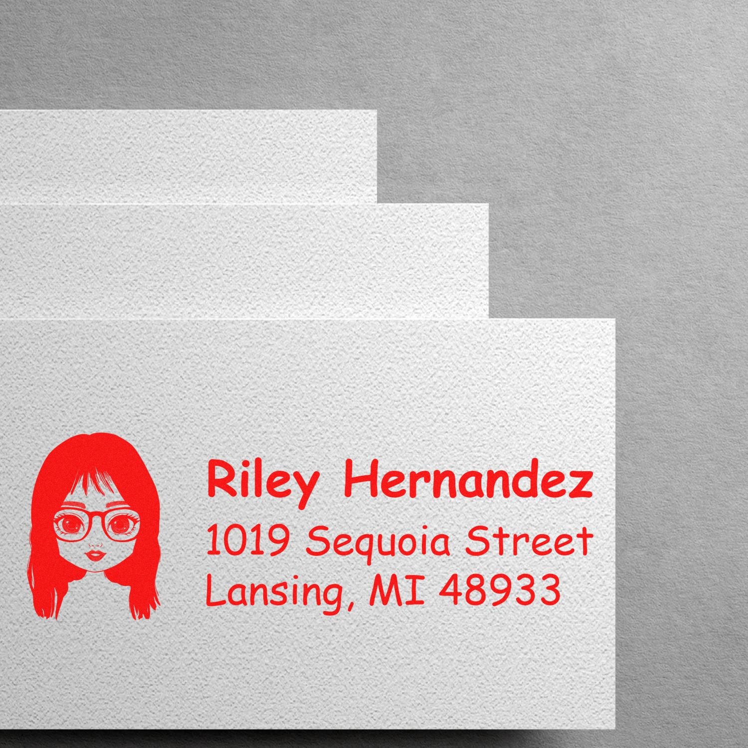 Custom address rubber stamp with cartoon girl icon, featuring Riley Hernandez and Lansing, MI mailing address in red ink.