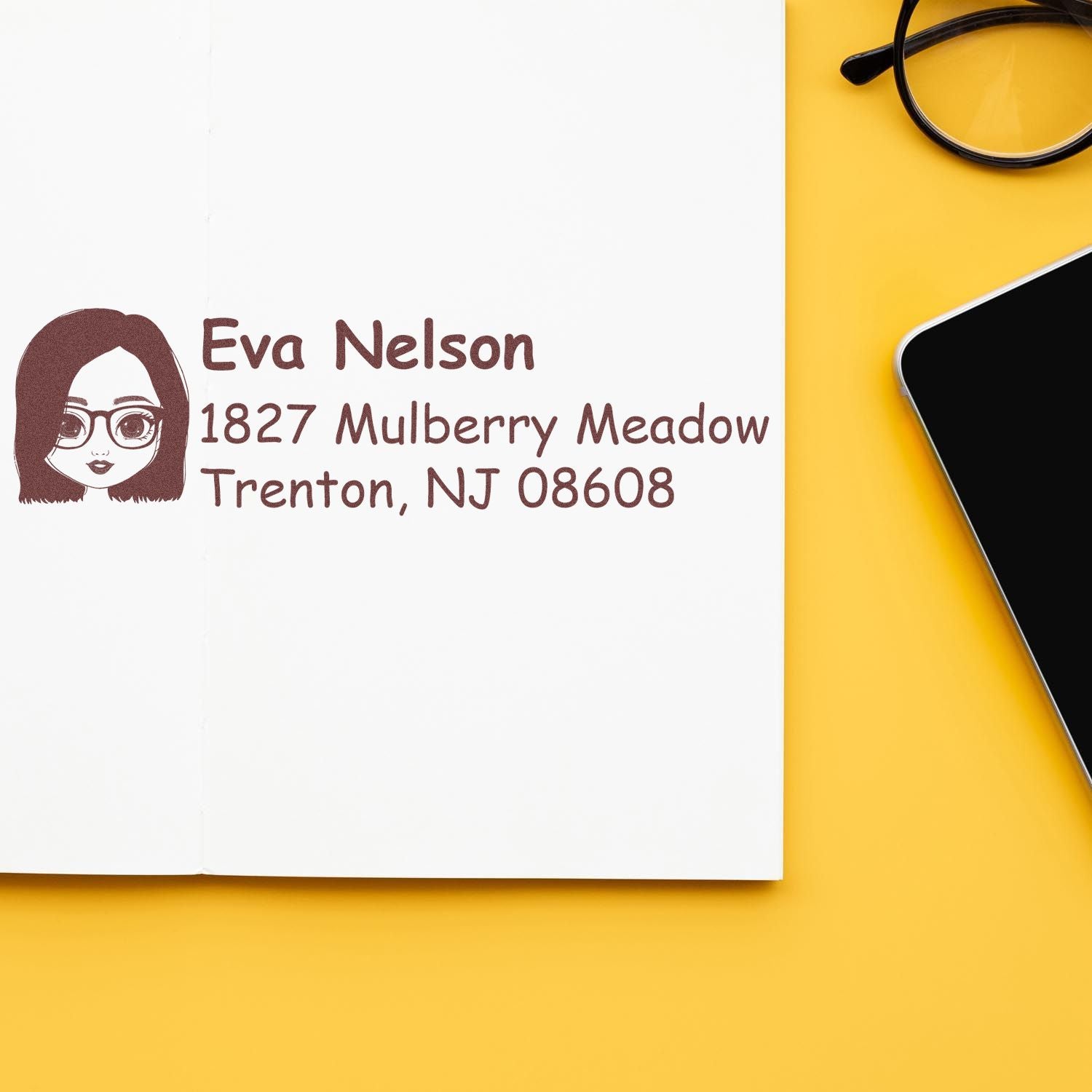 Personalized return address rubber stamp with illustrated avatar, stamped on notebook for Eva Nelson.