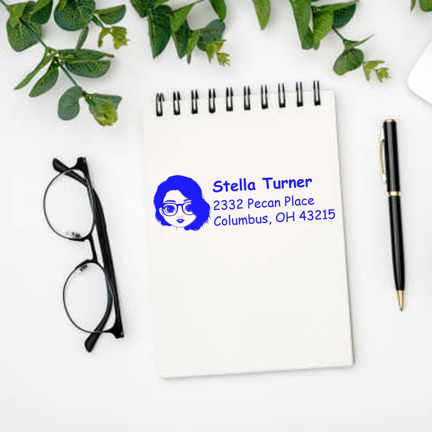 Personalized return address rubber stamp with name, Columbus OH address, and avatar design on a notebook.
