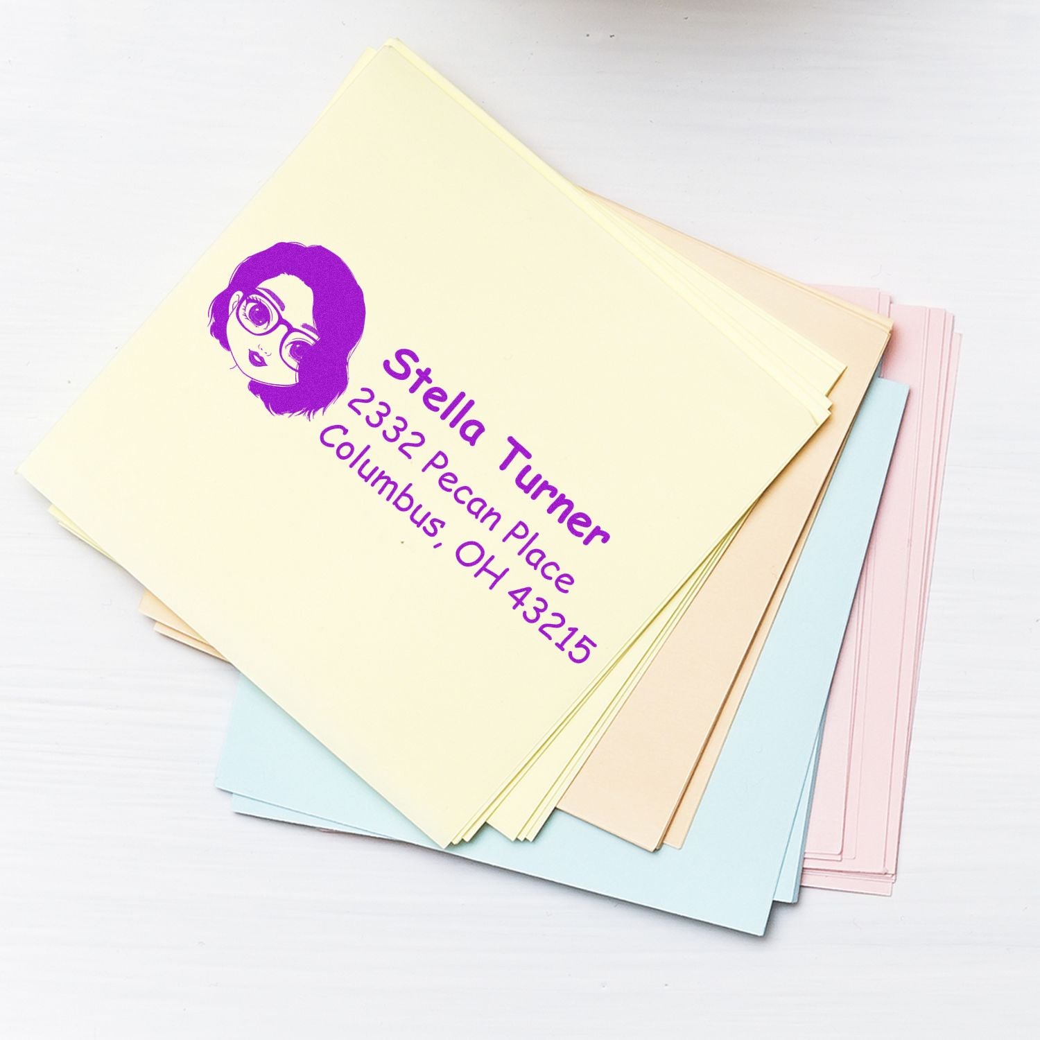 Custom return address rubber stamp for Stella Turner, Columbus, OH 43215, shown on pastel stationery stack.