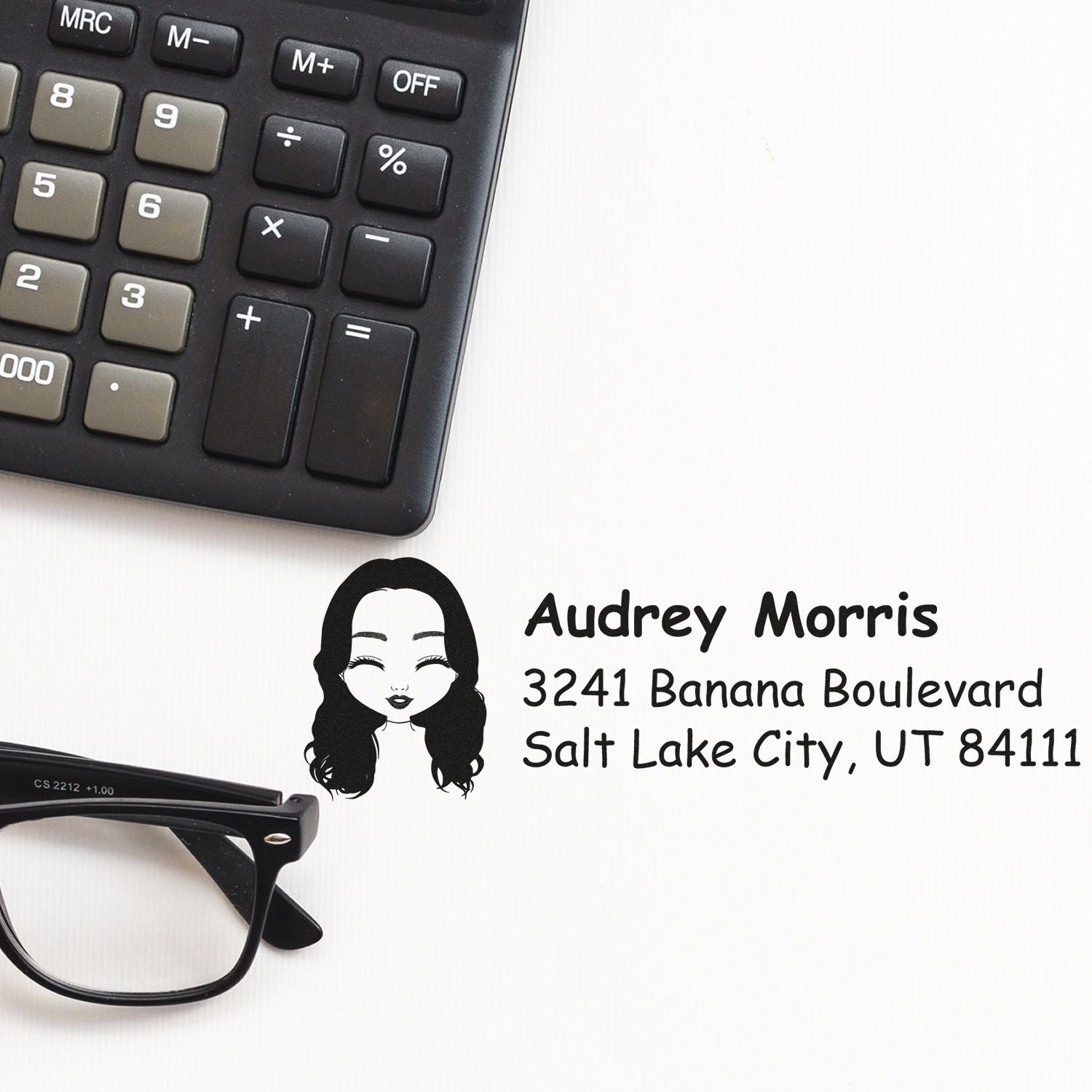 Custom return address rubber stamp with name, street address, and city, shown beside a calculator and eyeglasses.
