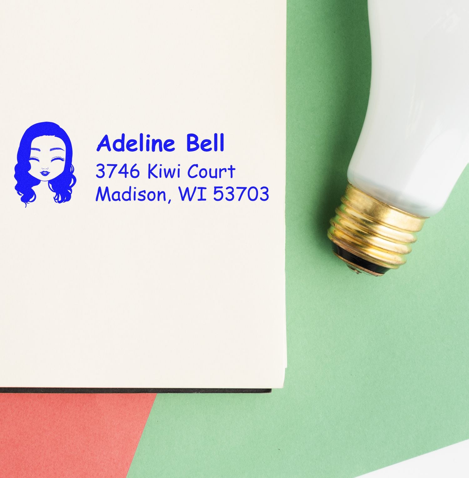 Personalized return address rubber stamp with avatar, name, and address, shown beside the stamp handle on paper.