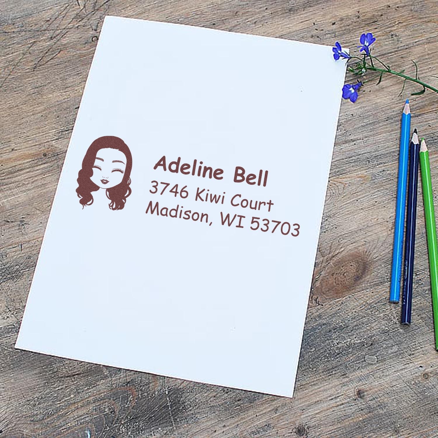 Custom address rubber stamp with name, return address, and portrait icon for personalized mailing.